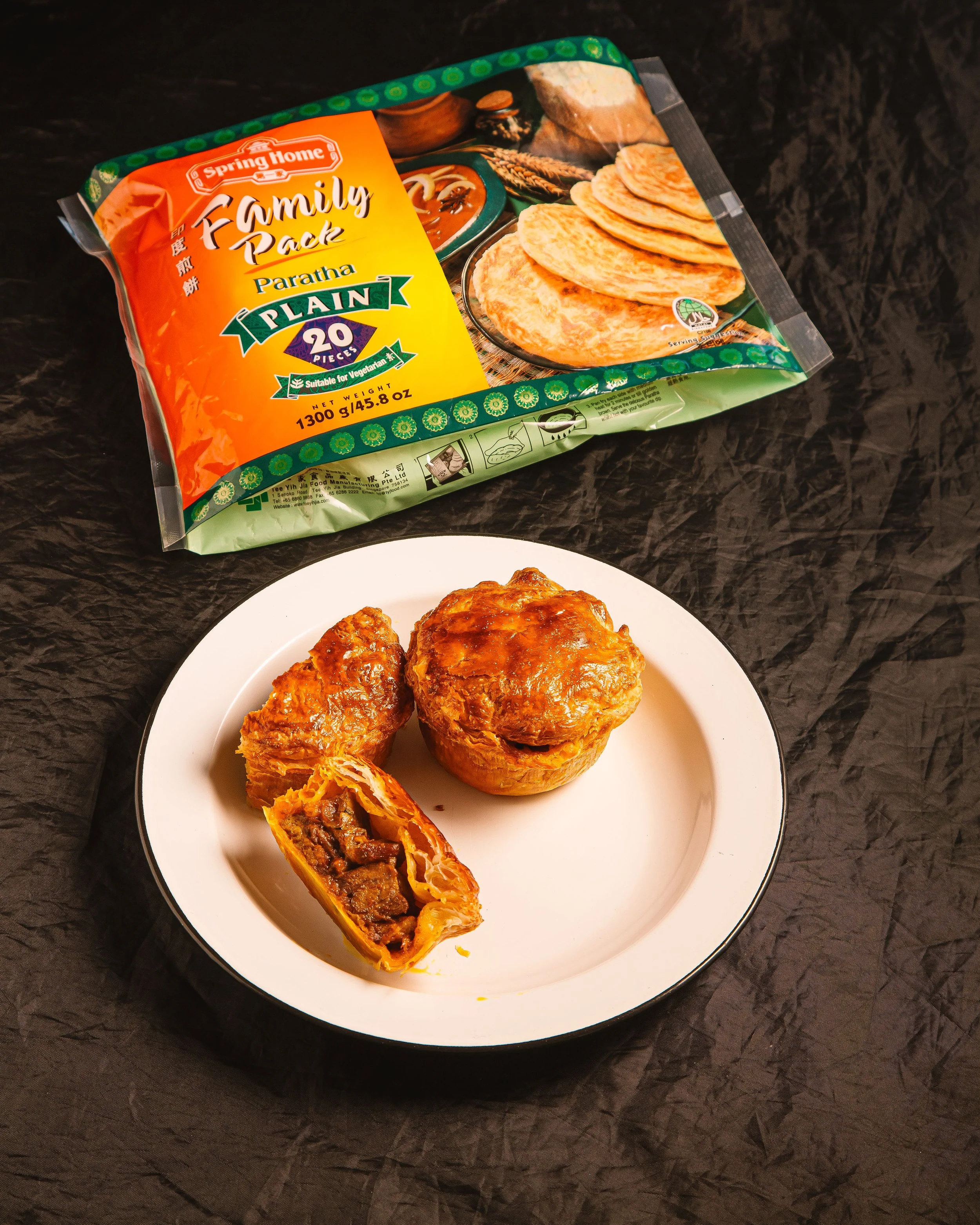 Unopened package of Spring Home family pack paratha flatbreads, and three cooked beef enchiladas on a white plate, one of which is cut open to reveal beef filling.