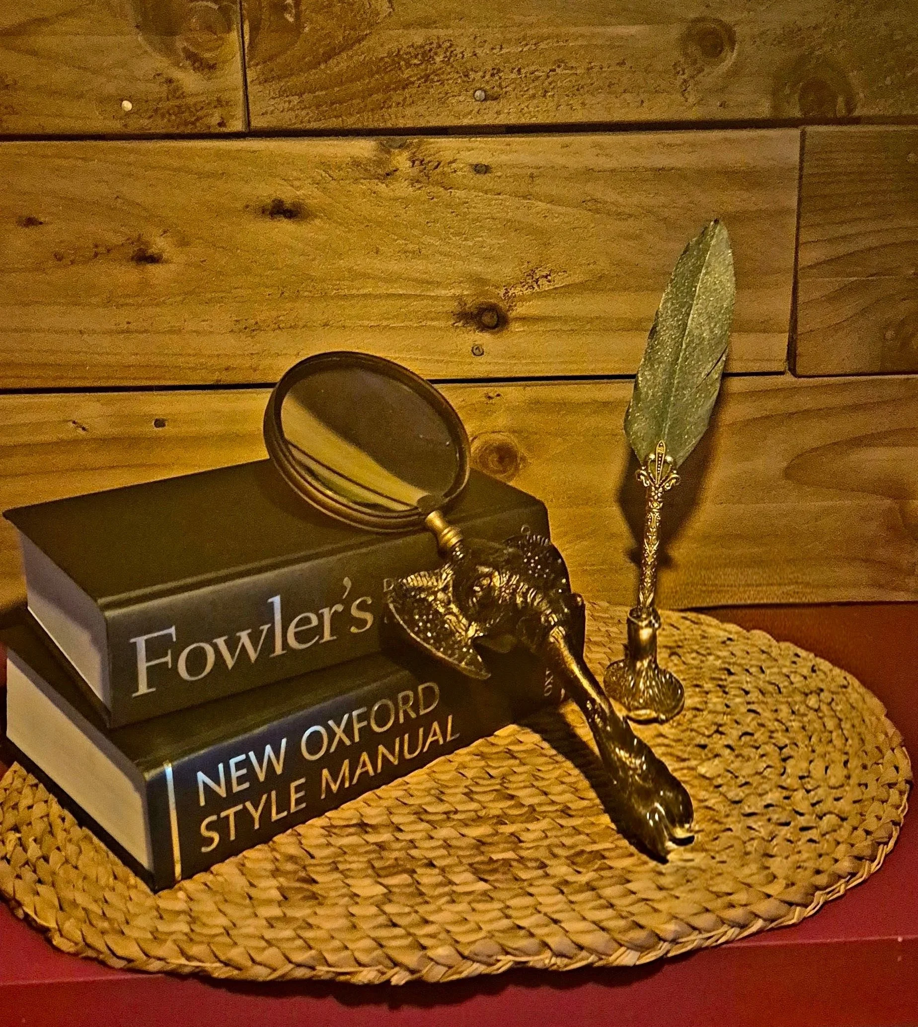 Quill and magnifying glass against famous copy-editing texts, Fowler's and New Oxford Style Manual