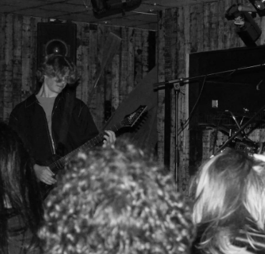 A person playing an electric guitar on stage at a music venue