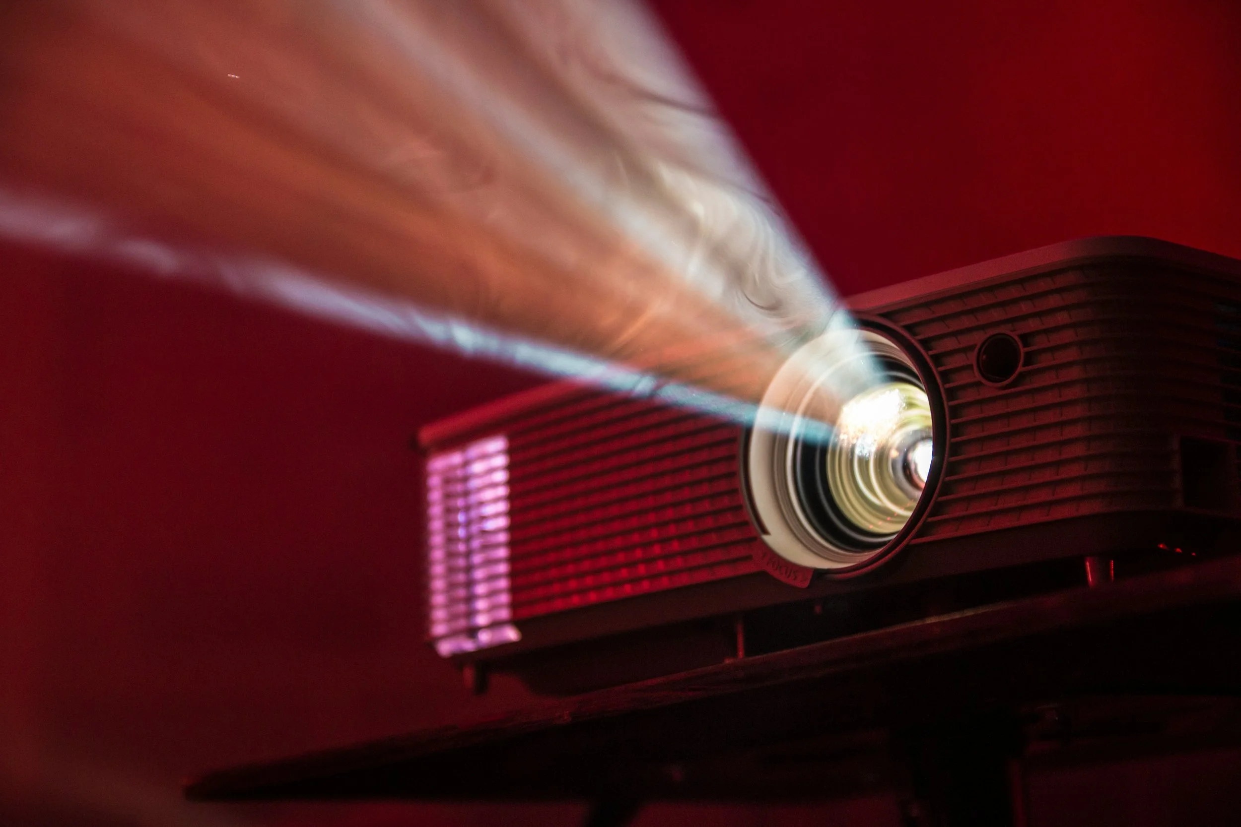 A modern projector emitting a bright beam of light onto a screen or surface.