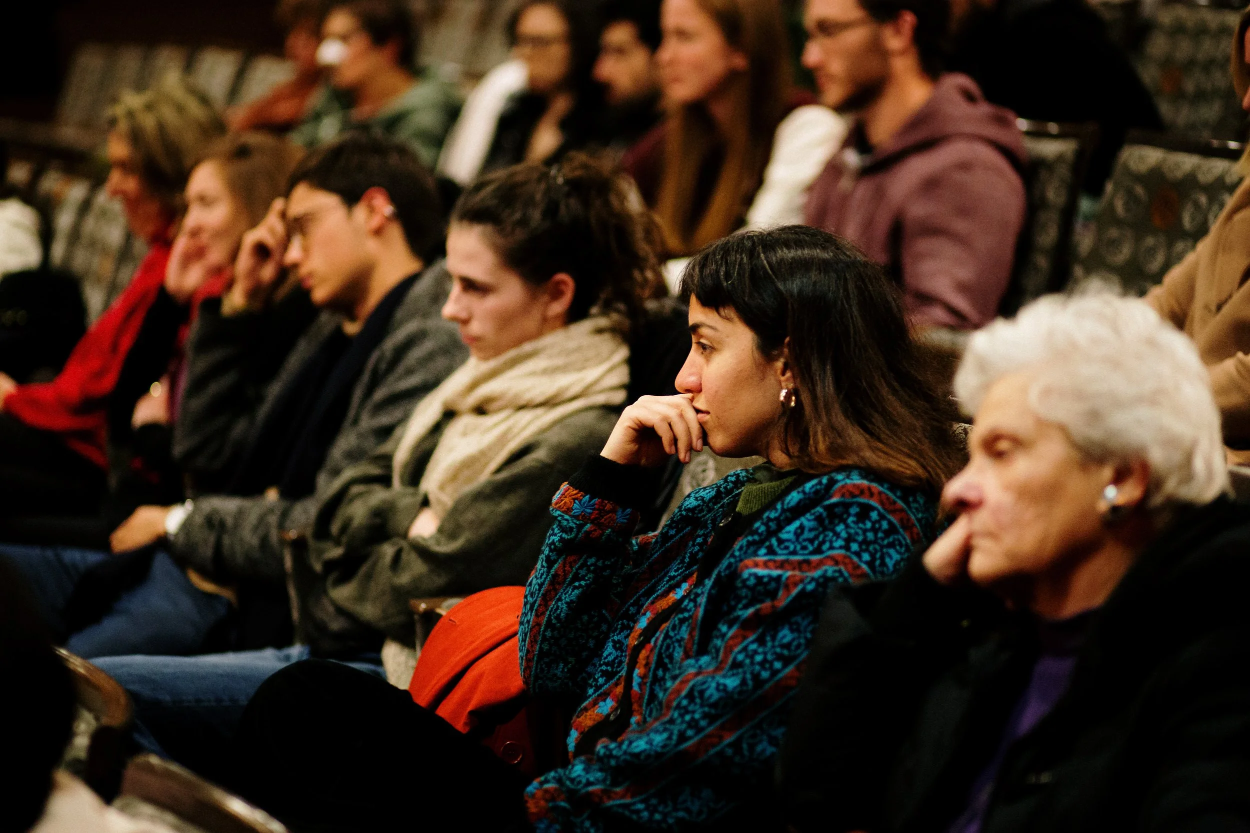 People sitting in an audience, attentively listening during an event or presentation.