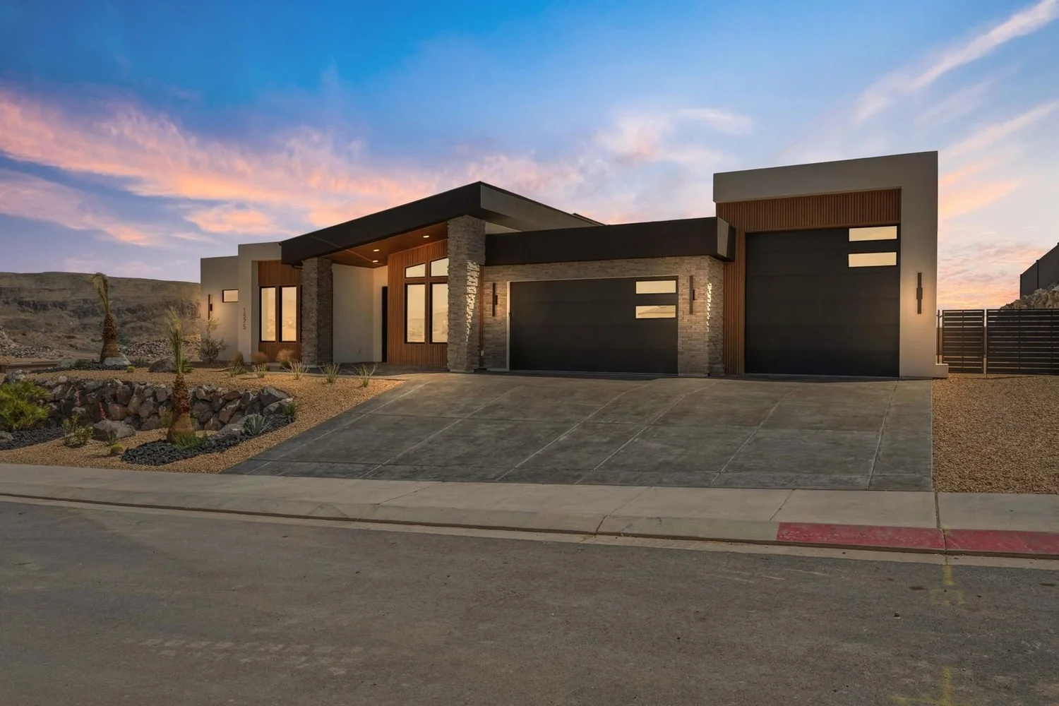 Modern home exterior with stone, stucco and wood accents designed by Urban Desert Homes in Southern Utah