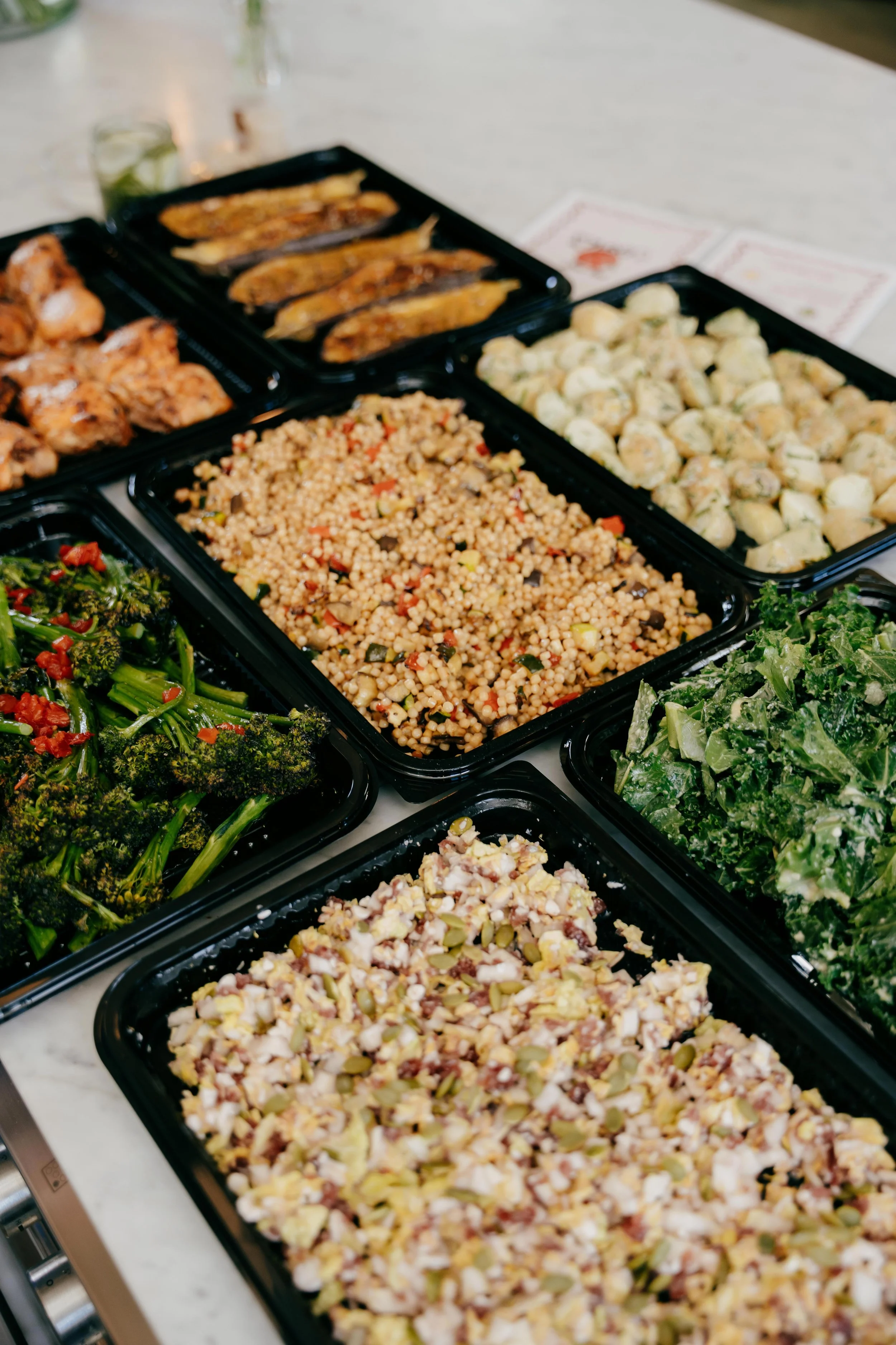 Tray of assorted salads and cooked vegetables on a white table