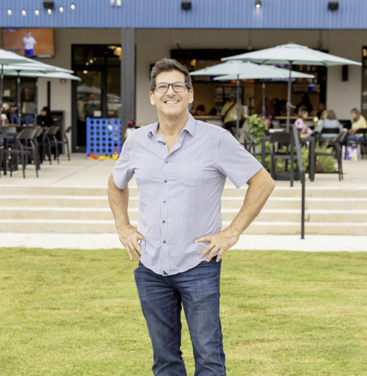 A man with glasses and dark hair smiling at a restaurant