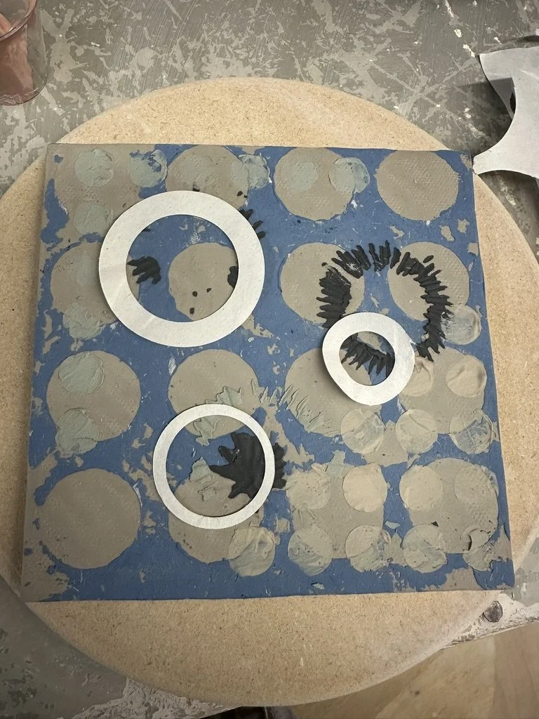 Metal rings and black bristles on a blue base with beige circles, possibly a brewing or manufacturing filter or disc.