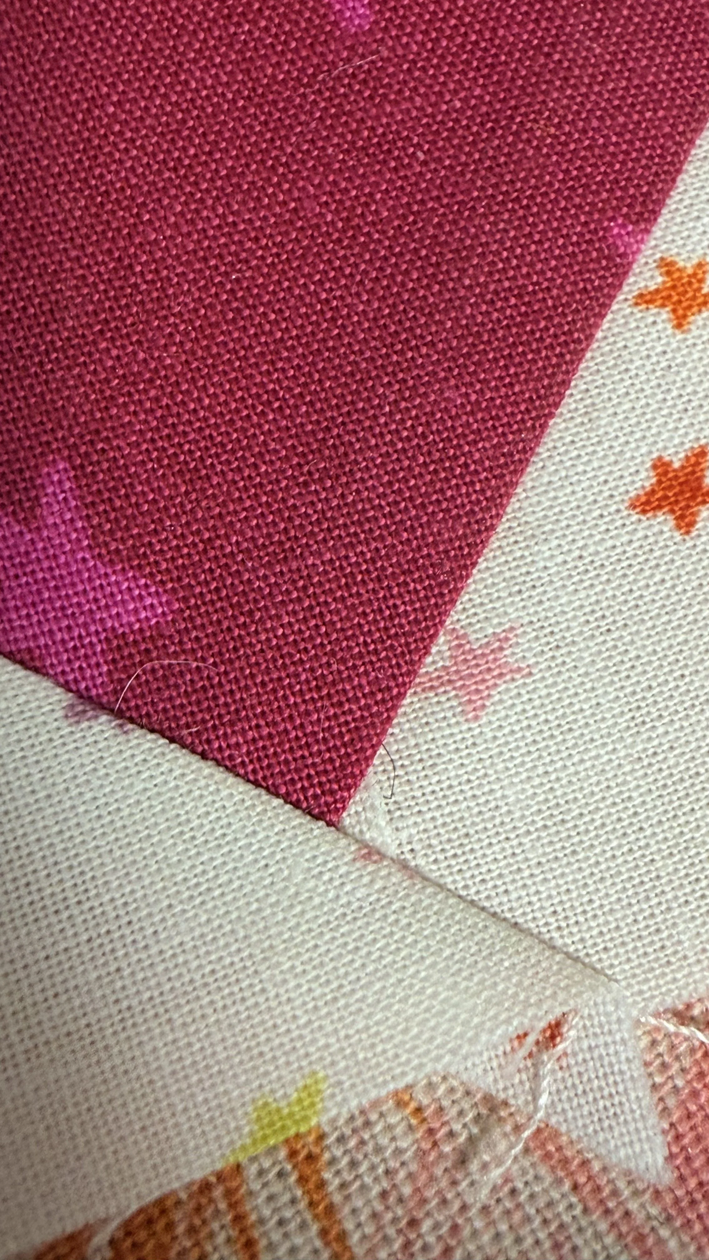 A closeup picture of the point on a flying geese quilt block, illustrating where the corner pieces of fabric create a small flap of overlapping fabric only a few threads wide.