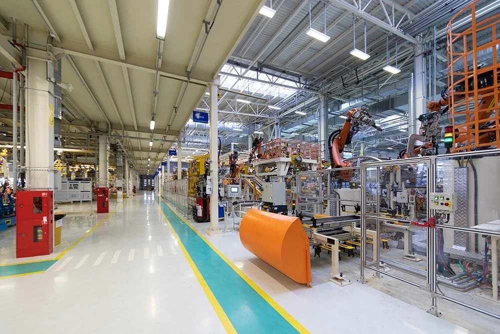 Industrial factory with robotic arms and production equipment in a clean, well-lit facility.