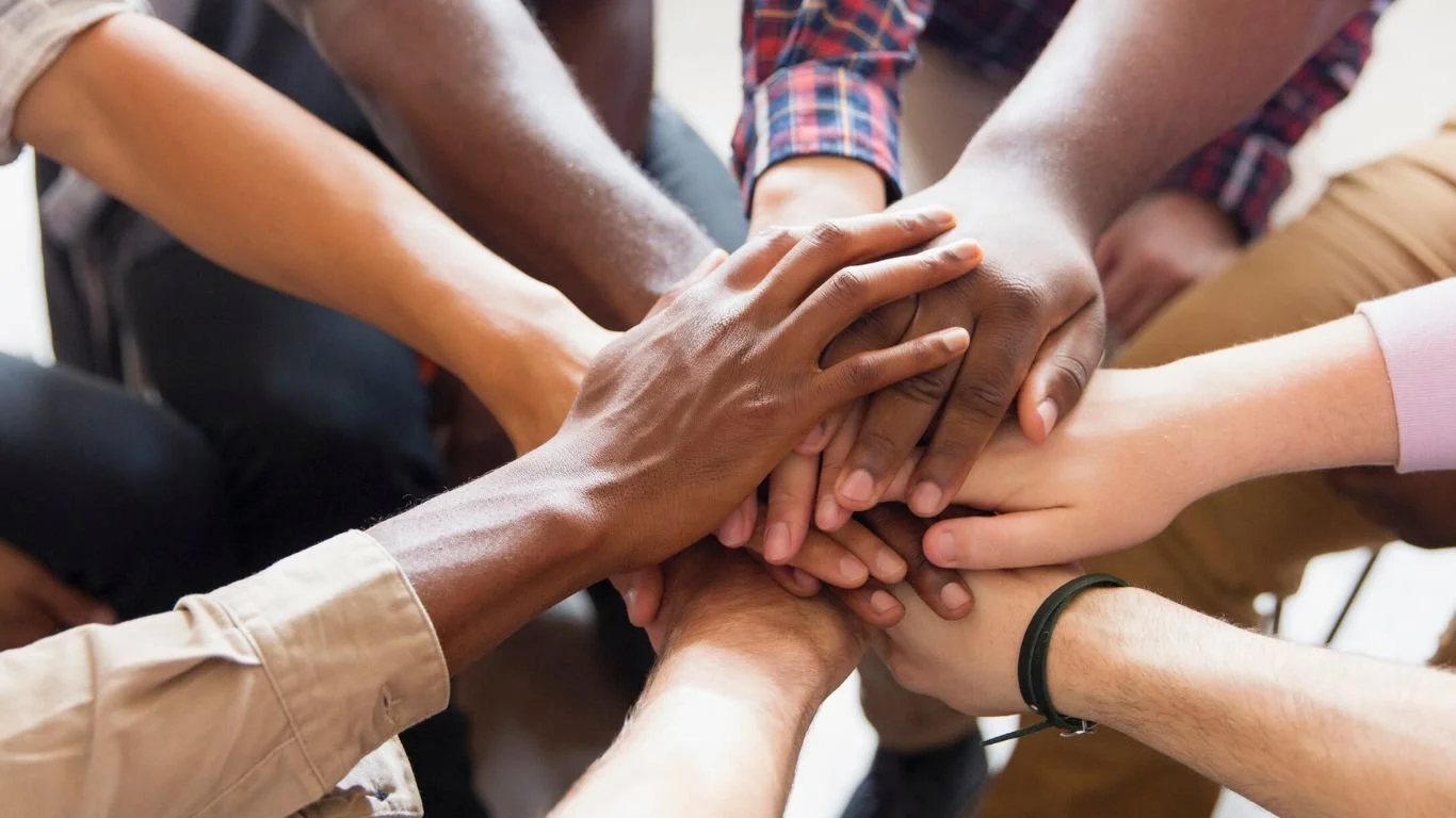 Multiple diverse hands stacked together in a sign of unity and teamwork.