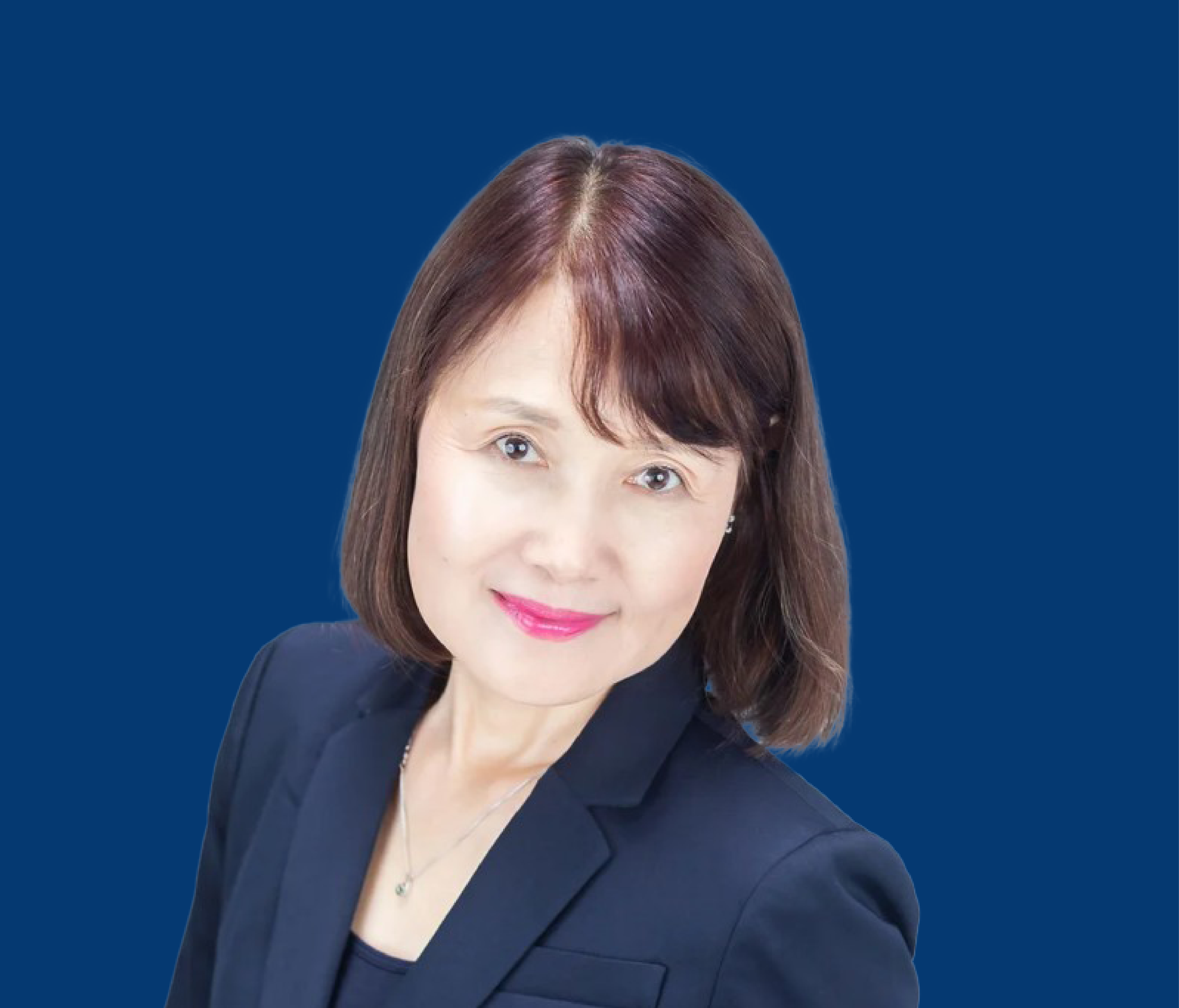 A woman with shoulder-length brown hair, wearing a dark blazer and a necklace, smiling against a solid blue background.