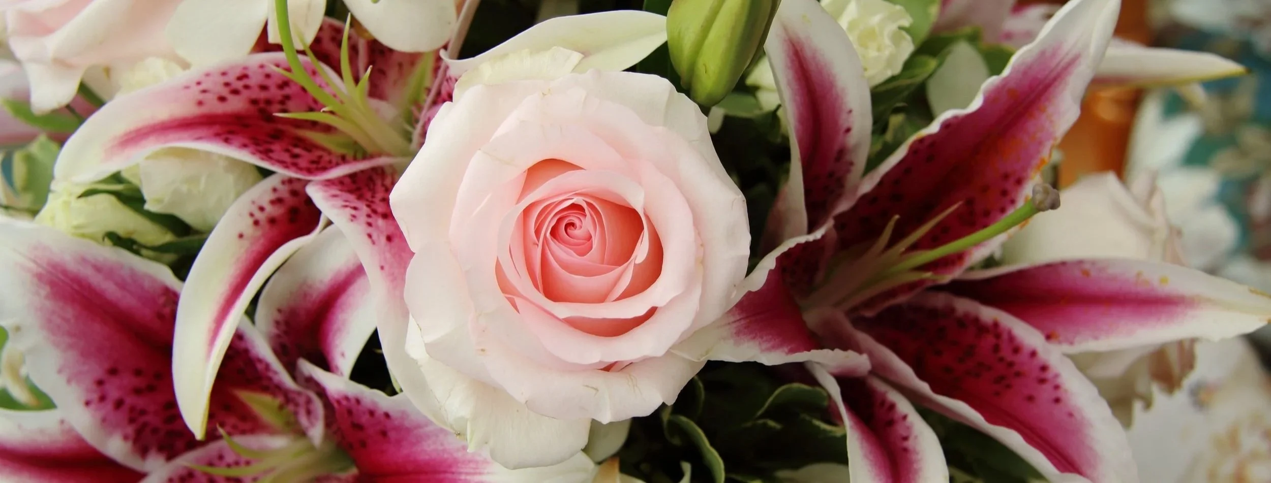 Close-up of a floral arrangement with pink roses and white and pink lilies.