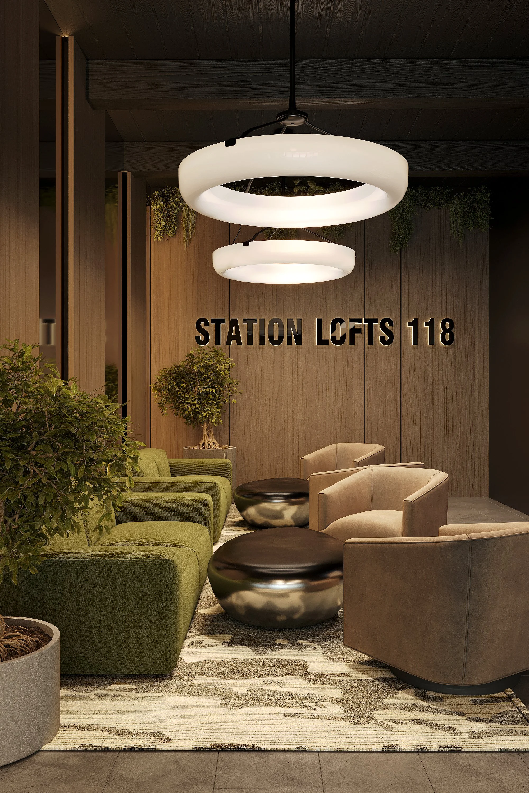 Lobby area with modern lighting fixtures, green and beige seating, small tables, potted plants, and a sign that reads 'STATION LOFTS 118' on a wood-paneled wall.