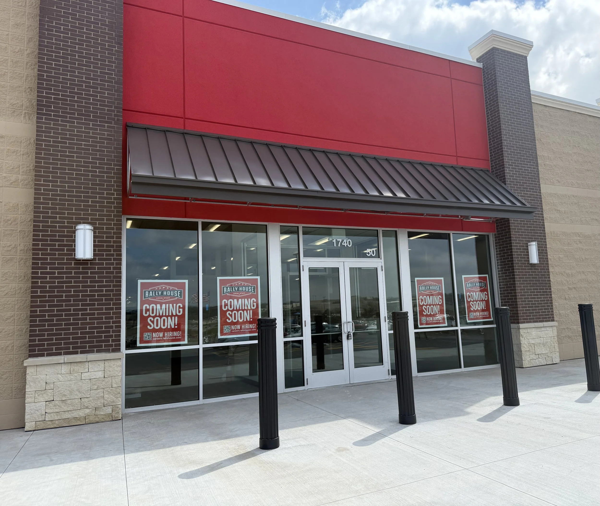 Awning installed at Rally House store entrance with signs that say 'Coming Soon! Now Hiring!' in the windows.