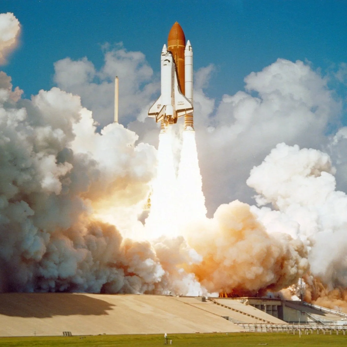 A space shuttle launches into the sky with flames and smoke billowing from its boosters.