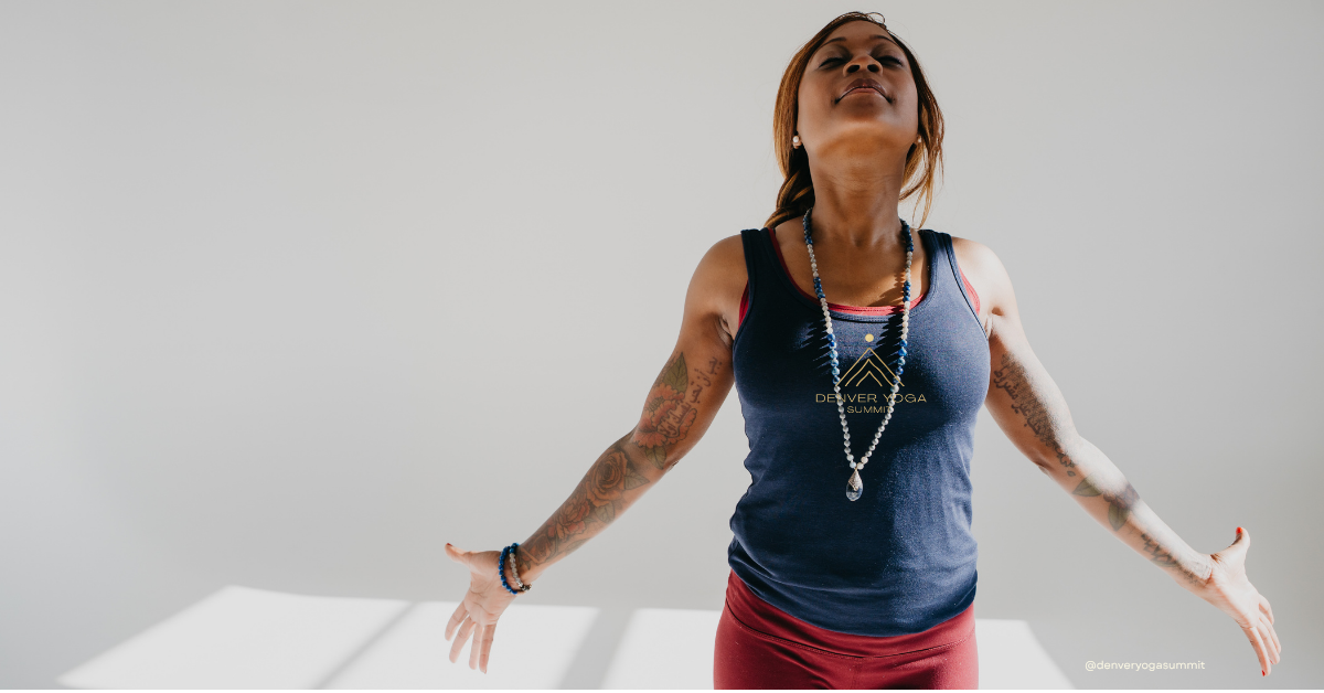 Yoga teacher in Denver Yoga Summit shirt with arms open and eyes closed, embodying brahmacharya for yoga teachers and the practice of protecting your energy.