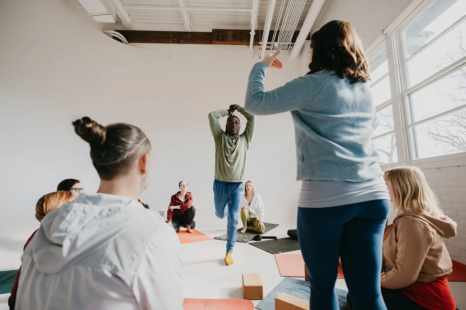 A yoga teacher cues a class, bringing aparigraha into her teaching.