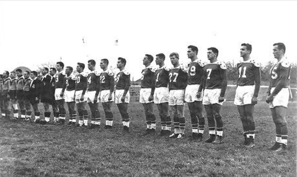 Black and white photo of a vintage soccer team standing in a line on a field.