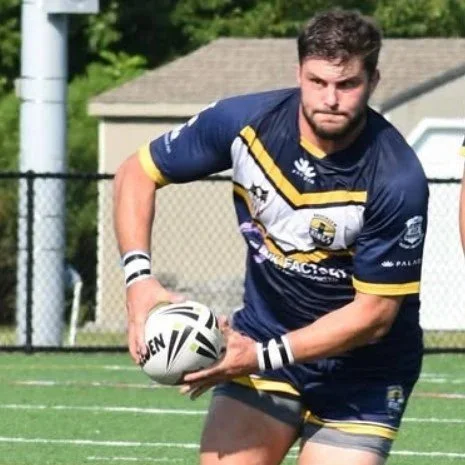 A rugby player holding a rugby ball on the field.