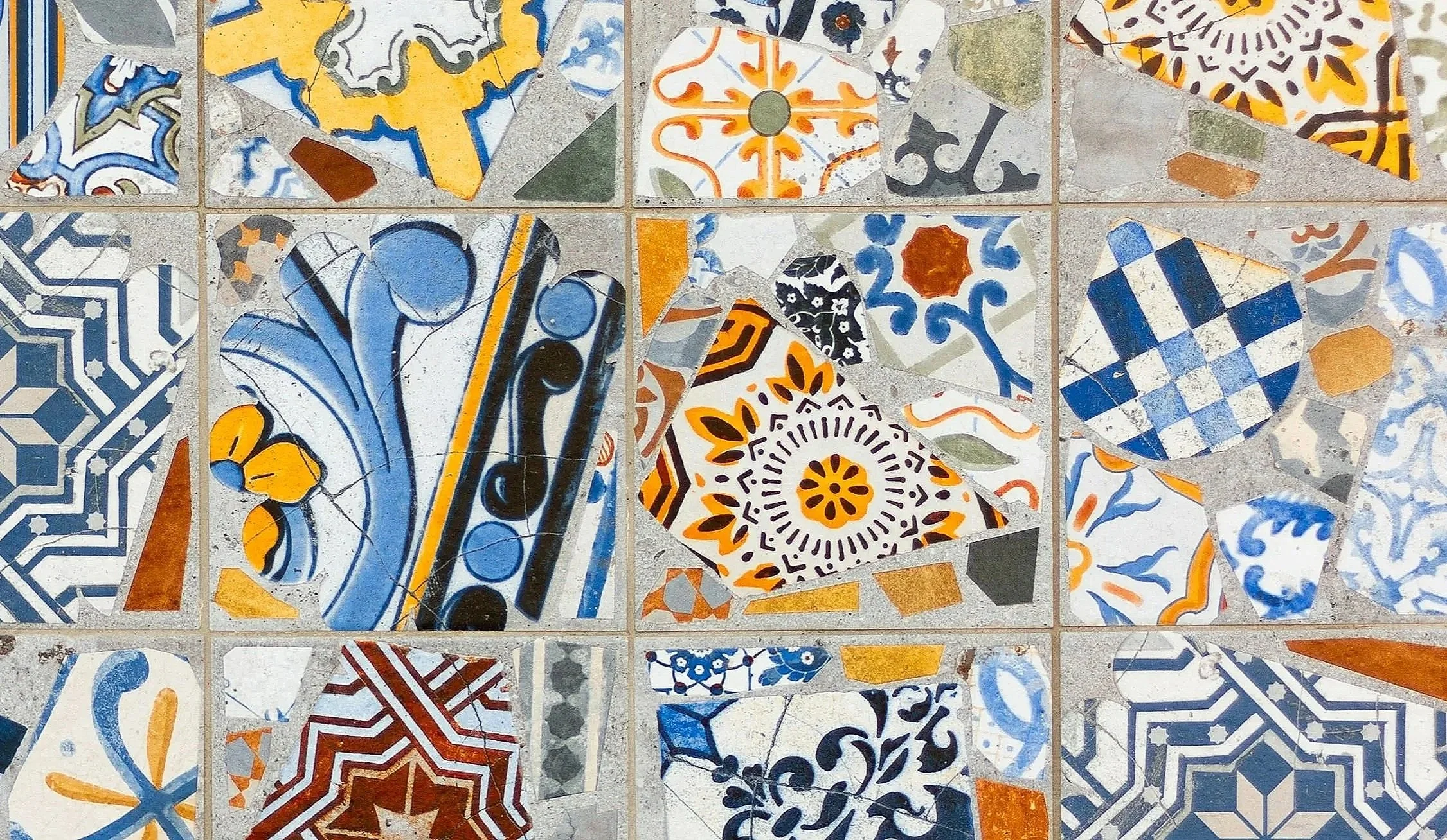 A decorative wall made of colorful square and round ceramic tiles with various intricate patterns in shades of blue, white, orange, black, and gray.