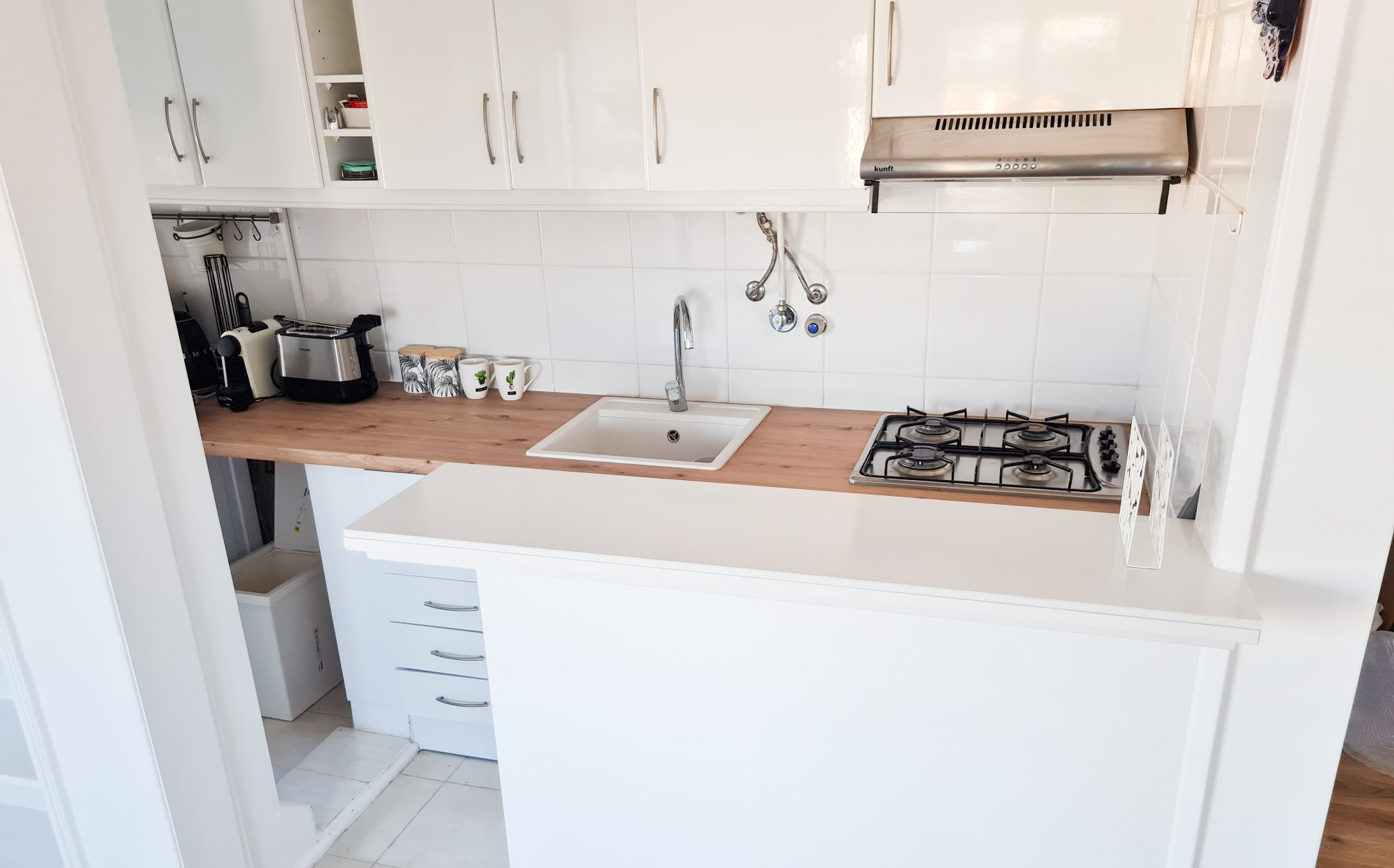 Kitchen with white cabinets, a wooden countertop, a small sink, a gas stove, and various small appliances like a toaster and a kettle.