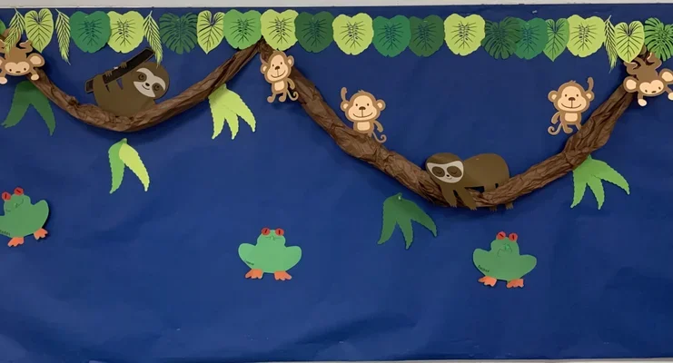 Decorative paper art of monkeys, sloths, frogs, and leaves on blue background.