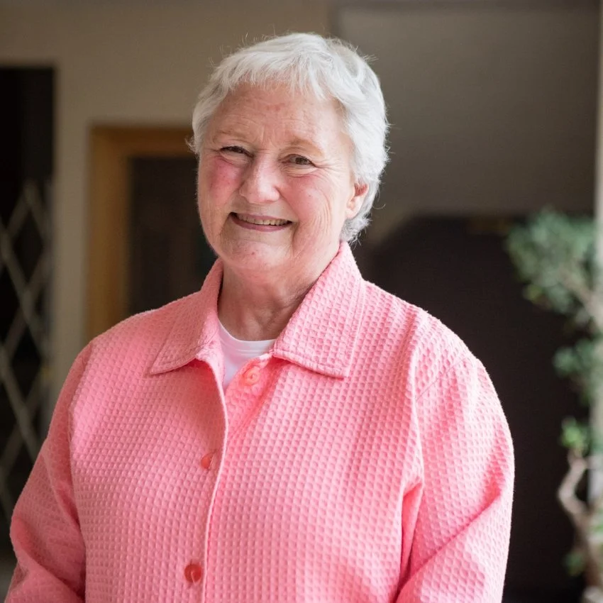 Laurie McRostie, the Special Projects Coordinator for Jericho Road Ministries, smiling at the camera, standing indoors with a blurred background.