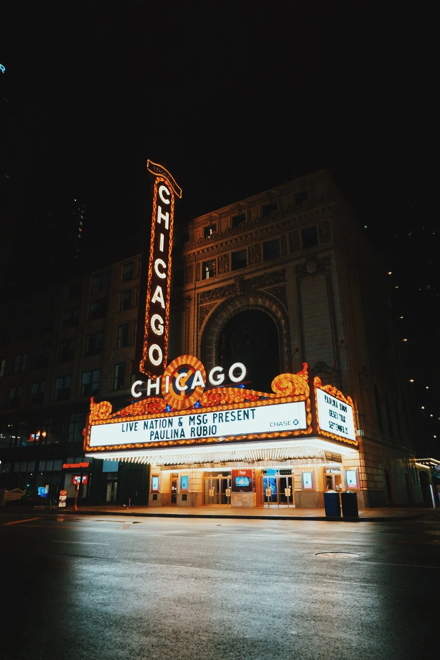Chicago theater marquee at night displaying upcoming concert featuring Paulina Rubio.