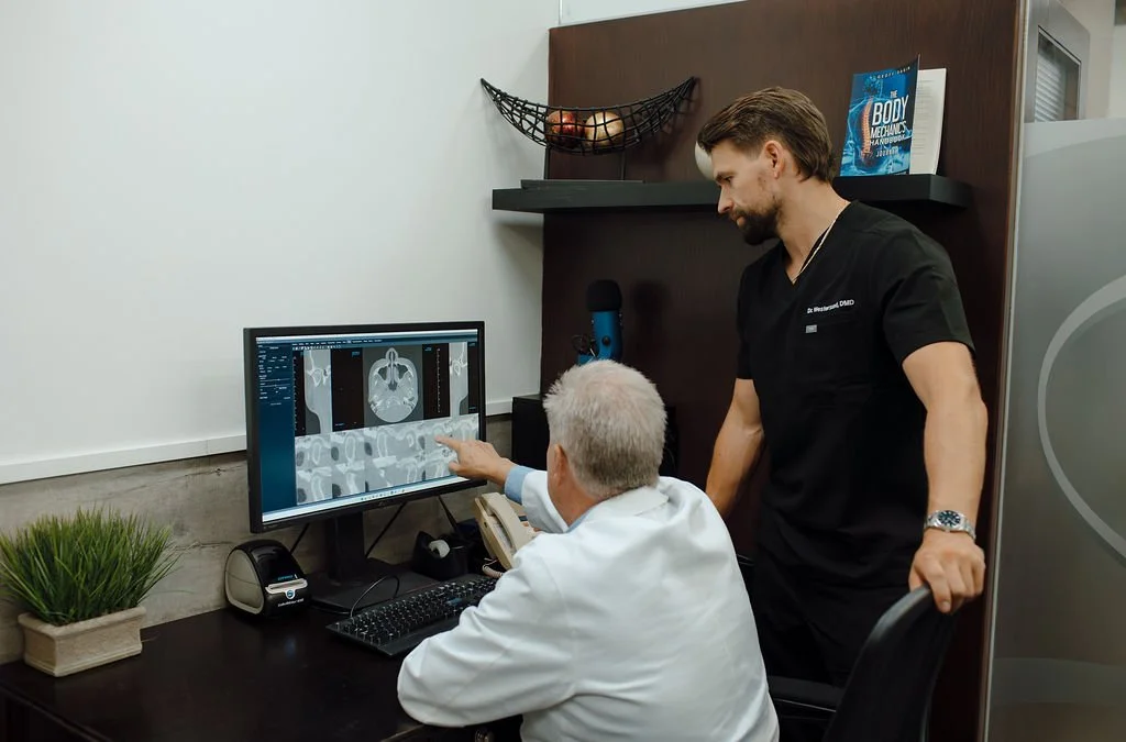 Doctor and healthcare professional reviewing a brain scan on a computer monitor in an office.