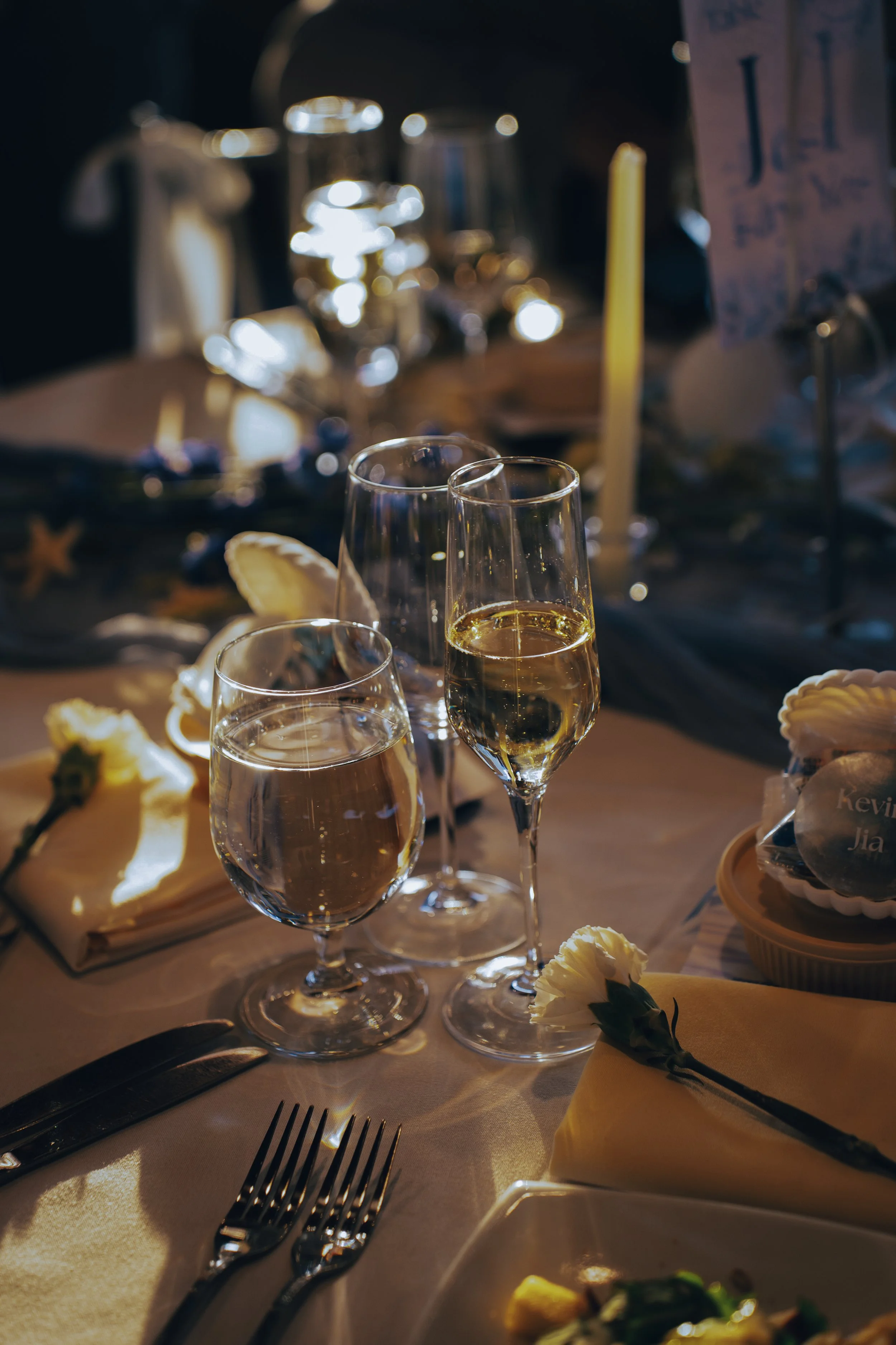 Glass of white wine and glass of champagne on a decorated table at a celebration or dinner event.