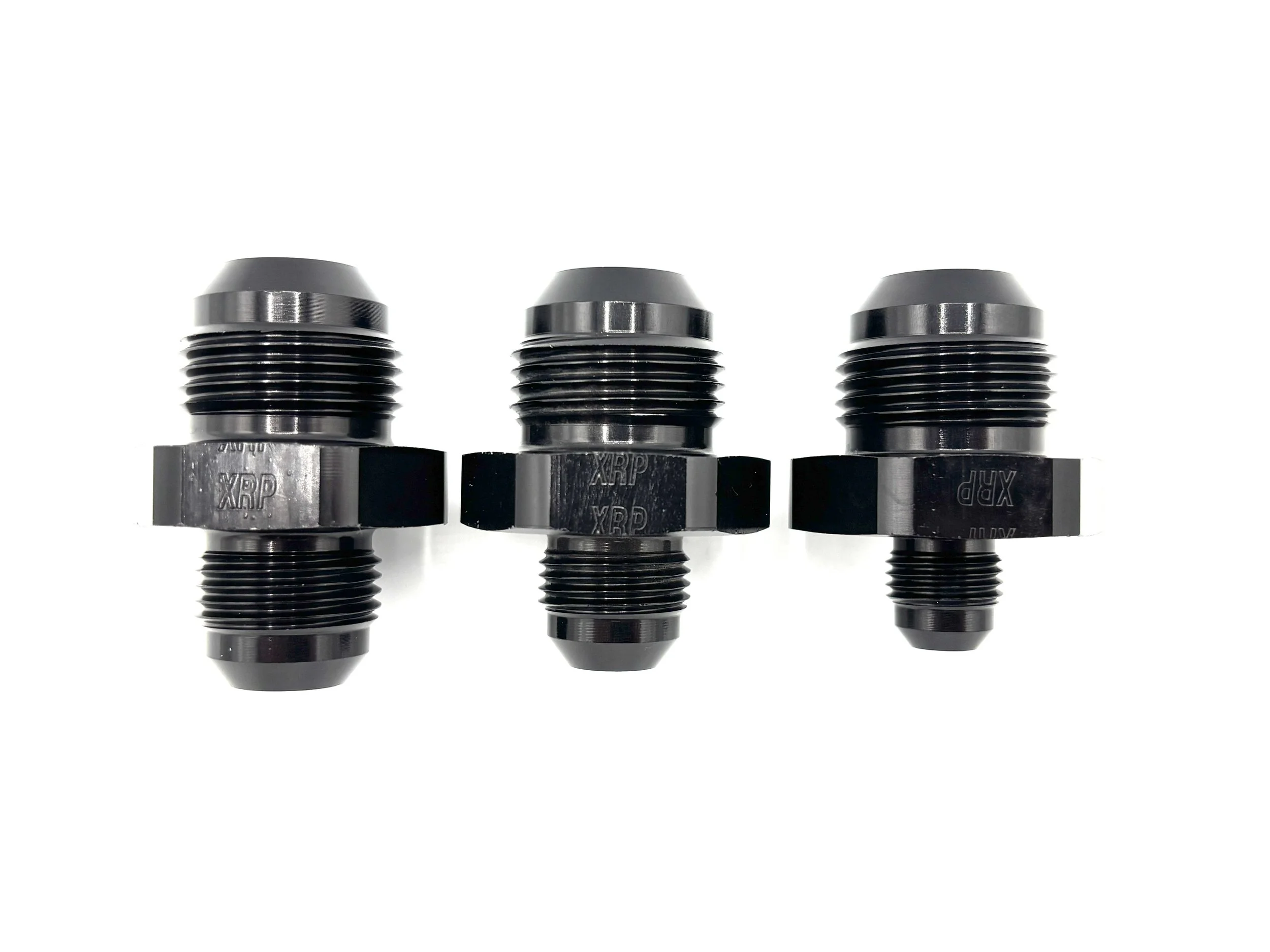 XRP straight -12AN male reducer fitting. Black in color. Various sizes from largest to smallest, left to right.