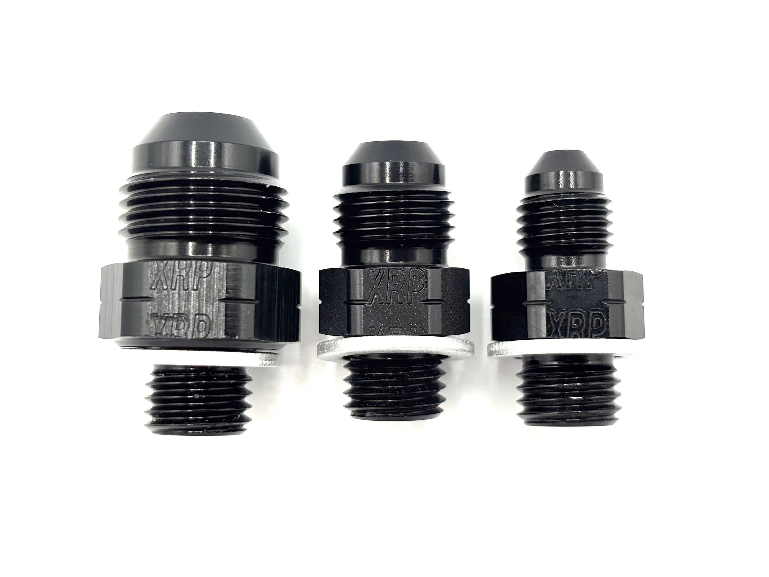 XRP straight AN male to M12 x 1.5 male with crush washer. Black in color. Various sizes from largest to smallest, left to right.