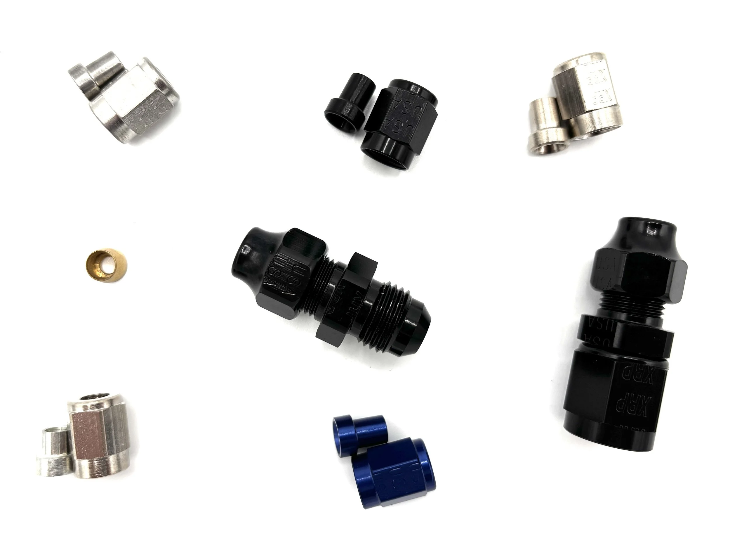 Various metal and plastic fittings and connectors, including black, silver, and blue components, arranged on a white surface.