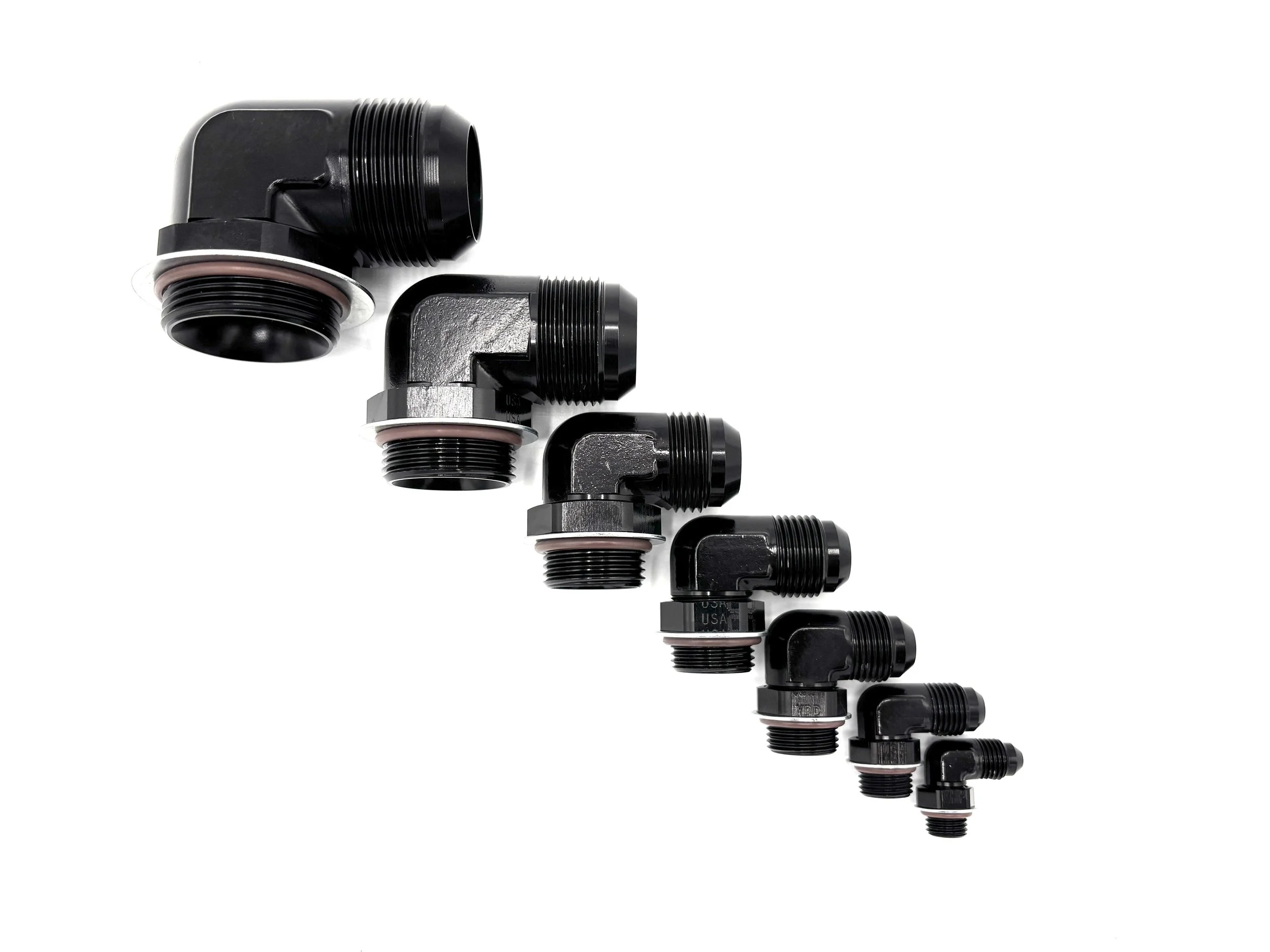 XRP 90 deg. AN male to o-ring boss low profile adapter fitting. Has nut, washer, and o-ring on it. Black in color. Various sizes from largest to smallest, left to right.