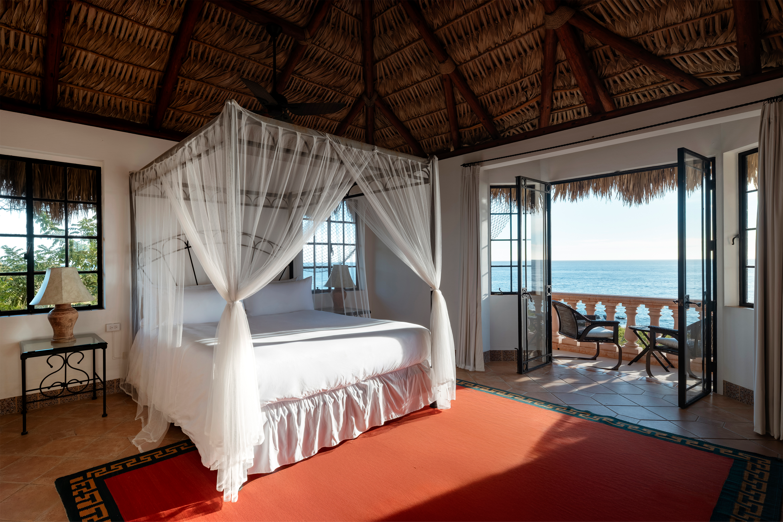 Interior of Copal Suite at La Valise Mazunte with king-size bed, wooden furnishings, and ocean view through open shutters.