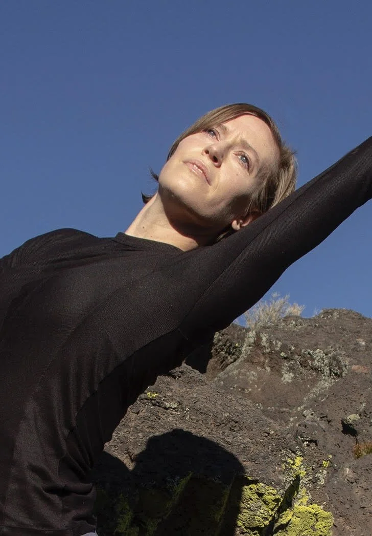 Close-up black and white portrait of a woman's face with long hair, looking directly at the camera.