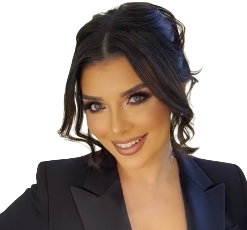 A woman with dark hair styled in loose waves, makeup, and a black blazer smiling at the camera against a black background.