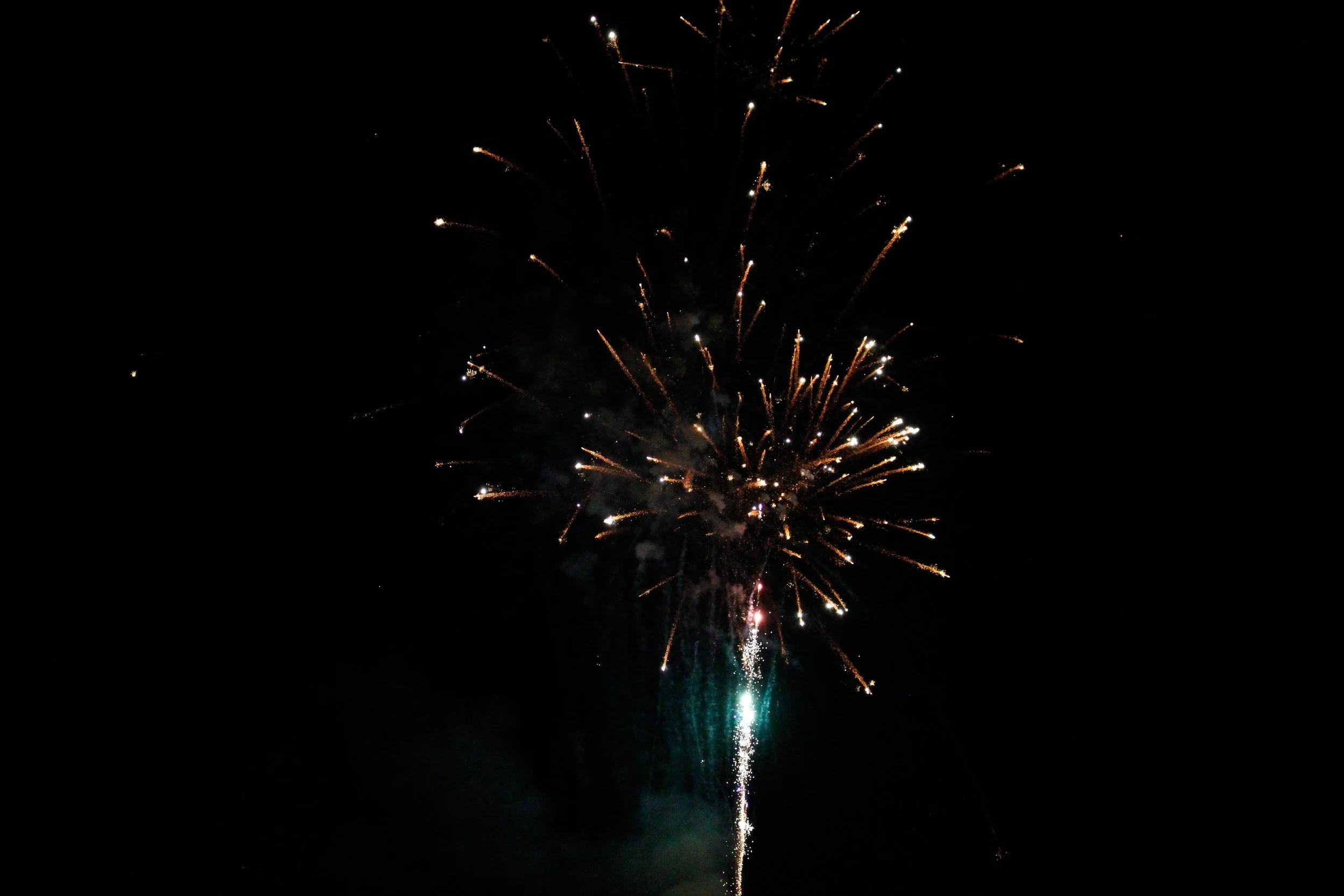 Fireworks exploding in the night sky with bright streaks of light against darkness.