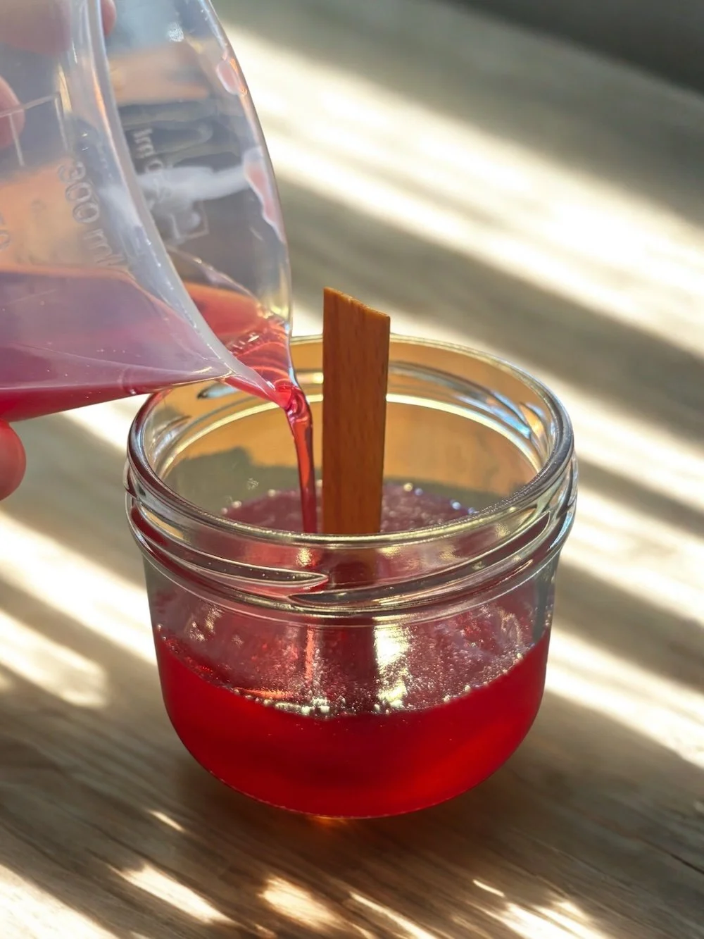 In ein Glas des CandleCrew Kerzenworkshops wird heißes Wachs gegossen.