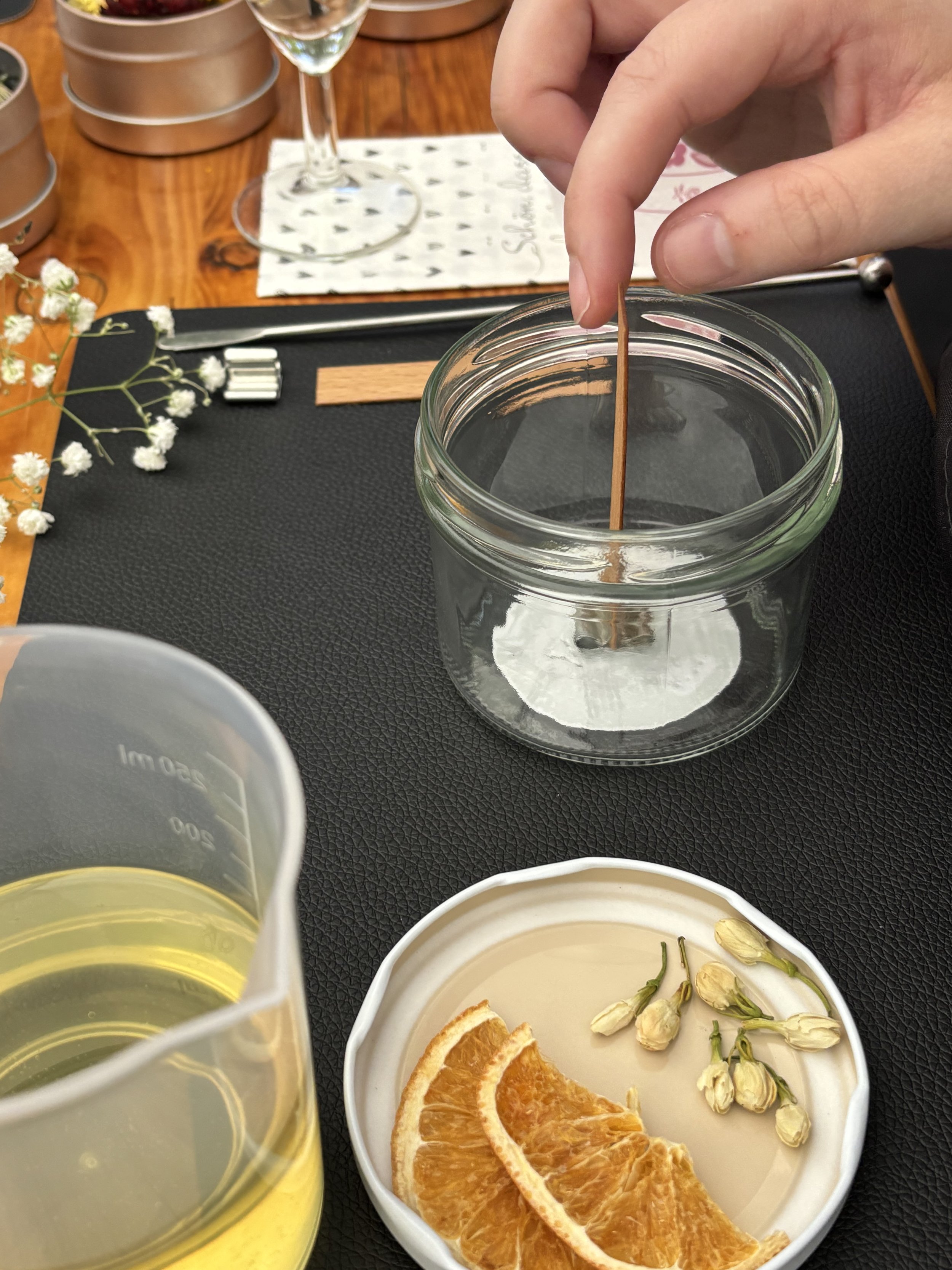 Eine Teilnehmerin des CandleCrew Kerzenworkshops bereitet ihre Kerze für das Einsetzen des Dochts vor.