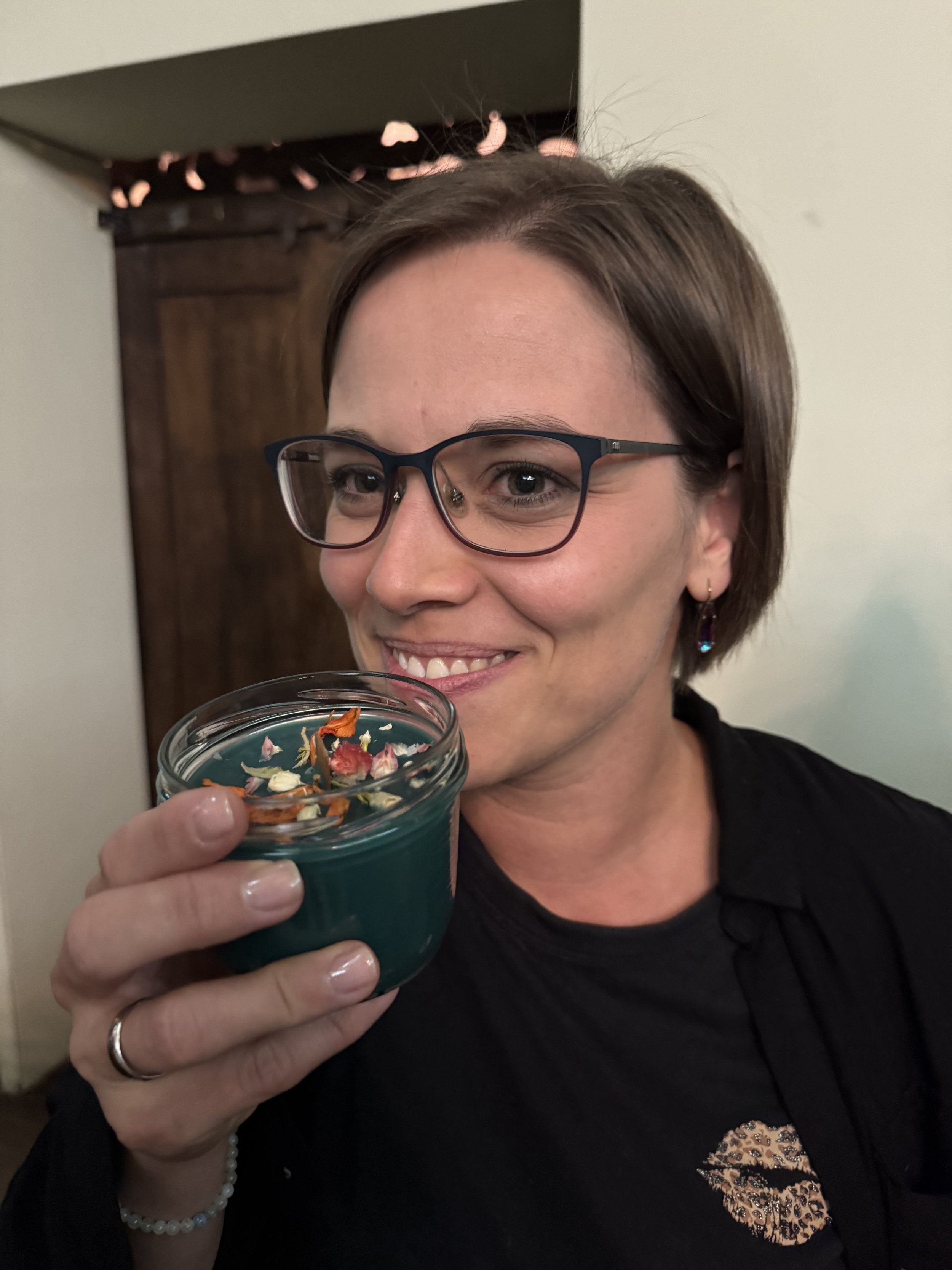 Eine begeisterte CandleCrew-Teilnehmerin hält lächelnd ihre Kerze in die Kamera.