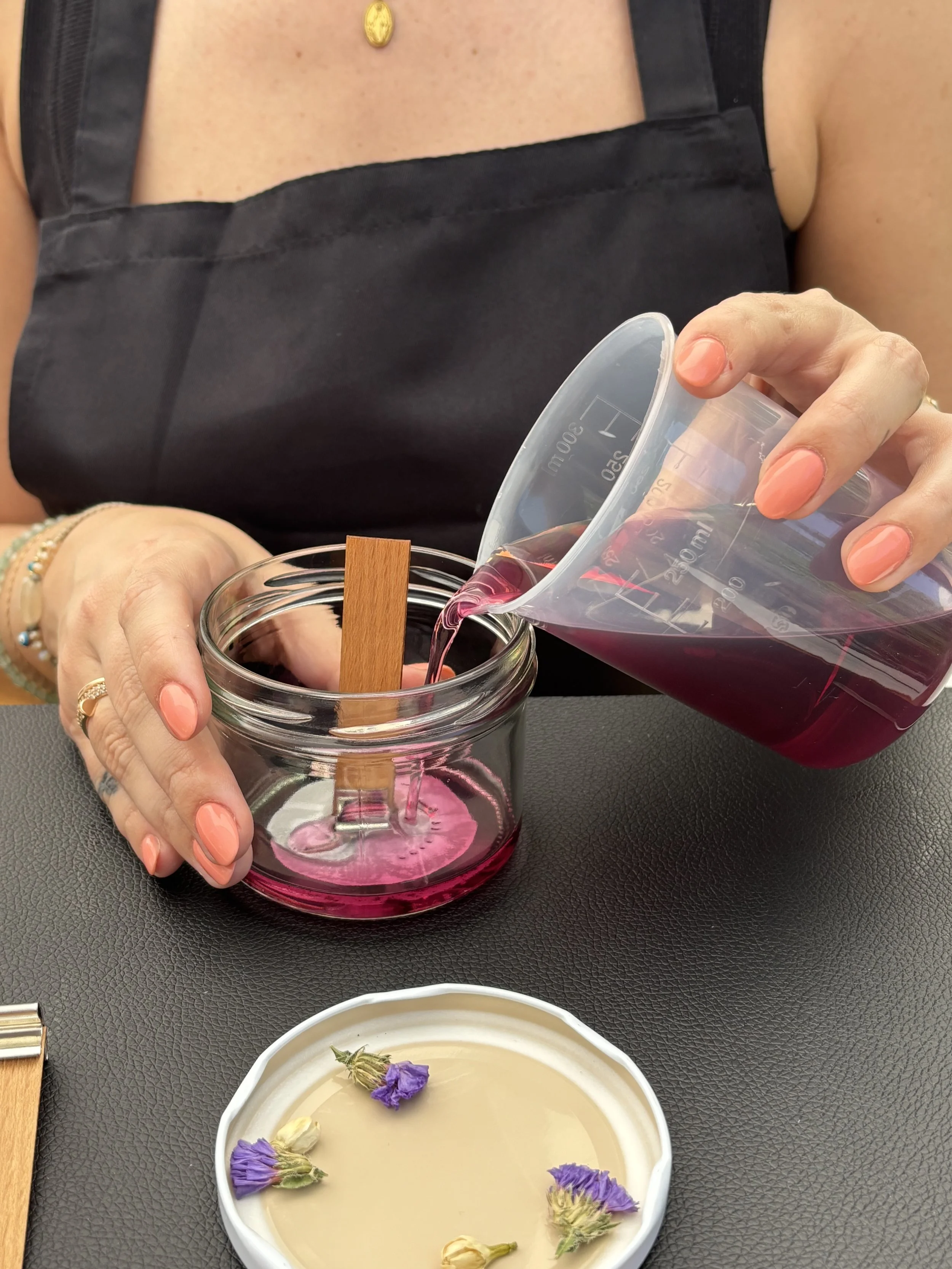 Eine Teilnehmerin des DIY-Workshops der CandleCrew schüttet flüssiges Wachs in ein Glas.