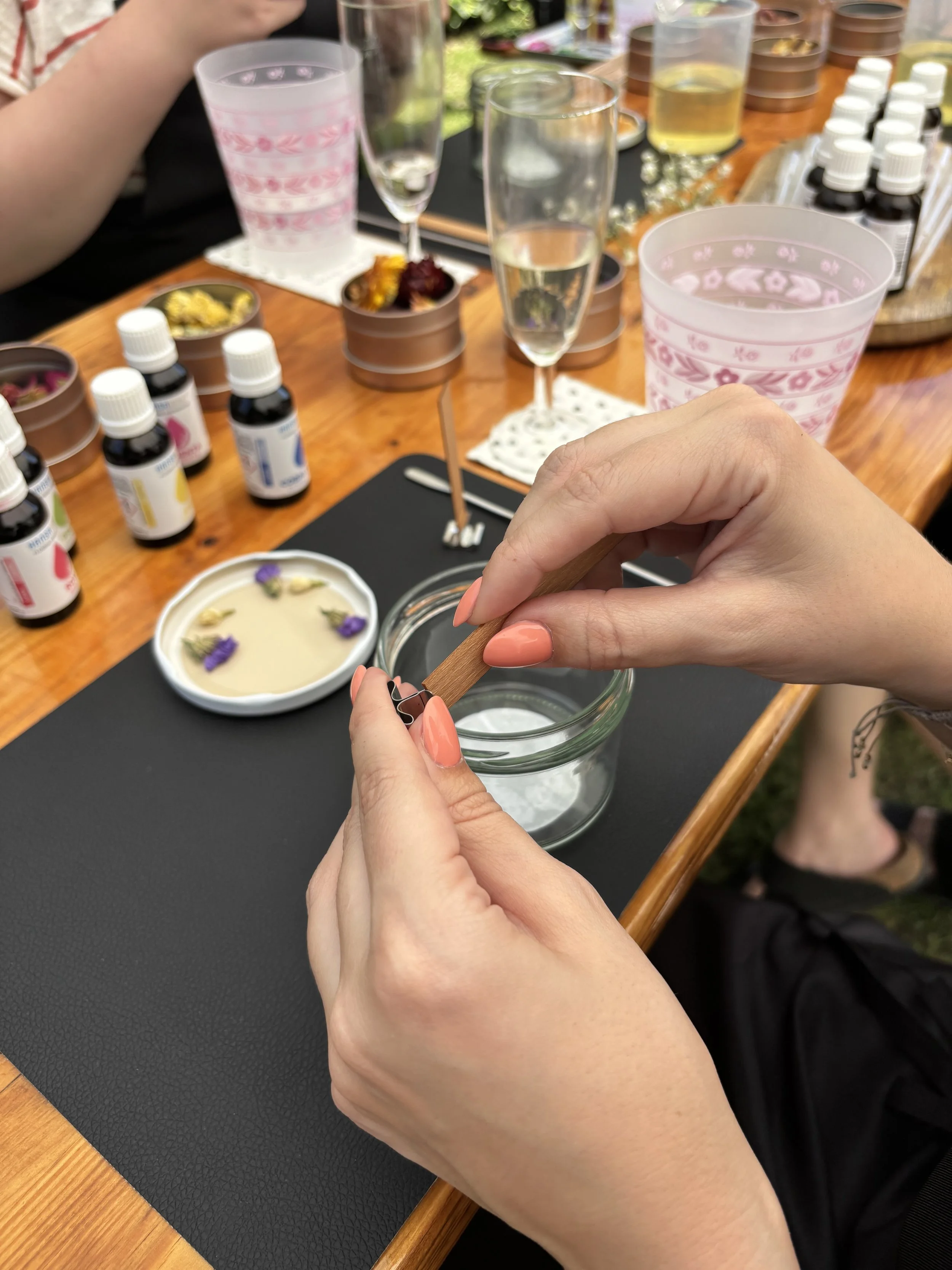 Zwei Hände bereiten den Docht vor, der in die selbst gemachte Kerze eingesetzt wird.