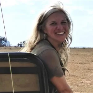 Amy Martinez Beal smiles with a grassland landscape behind her.