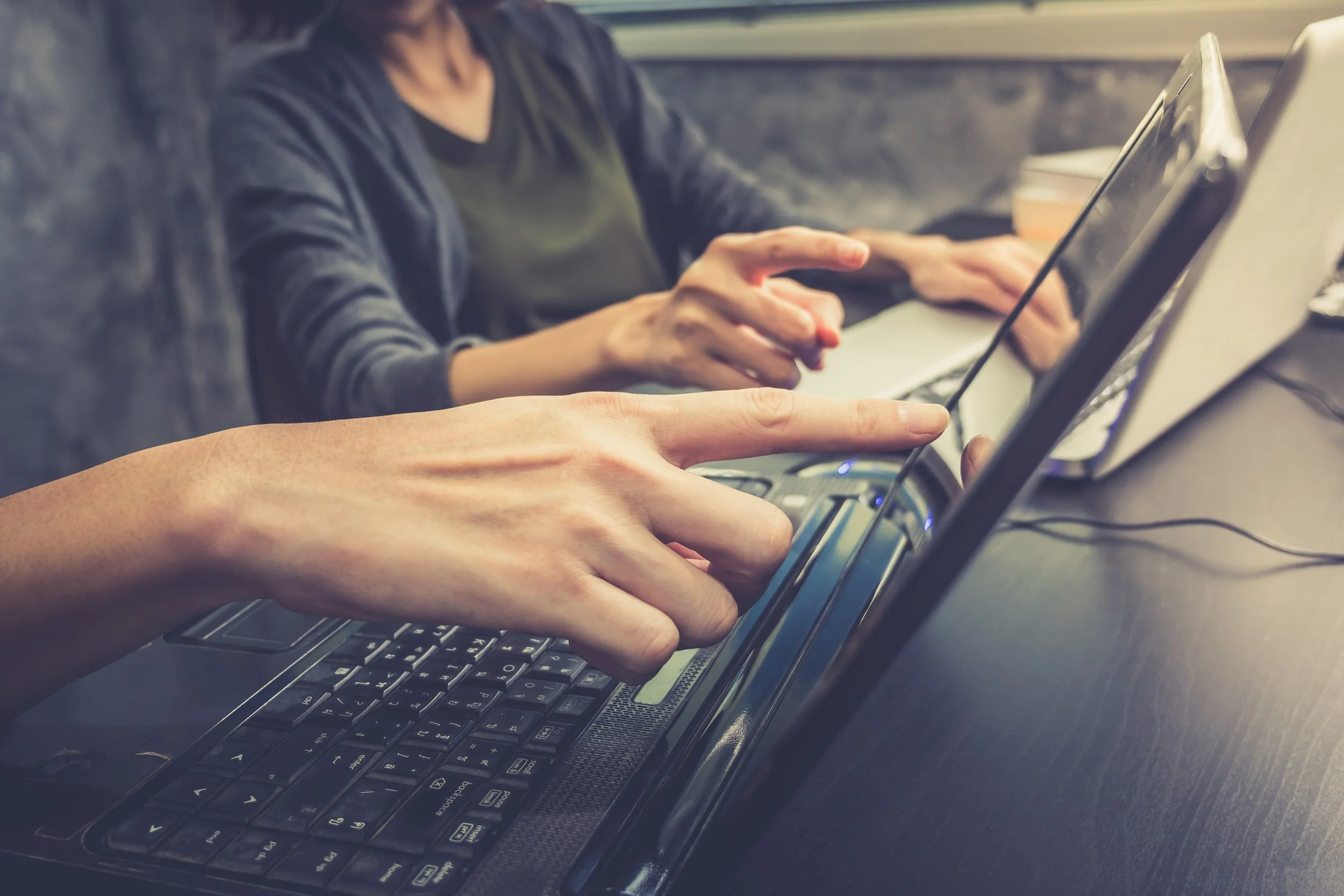 Two people review information on laptops.