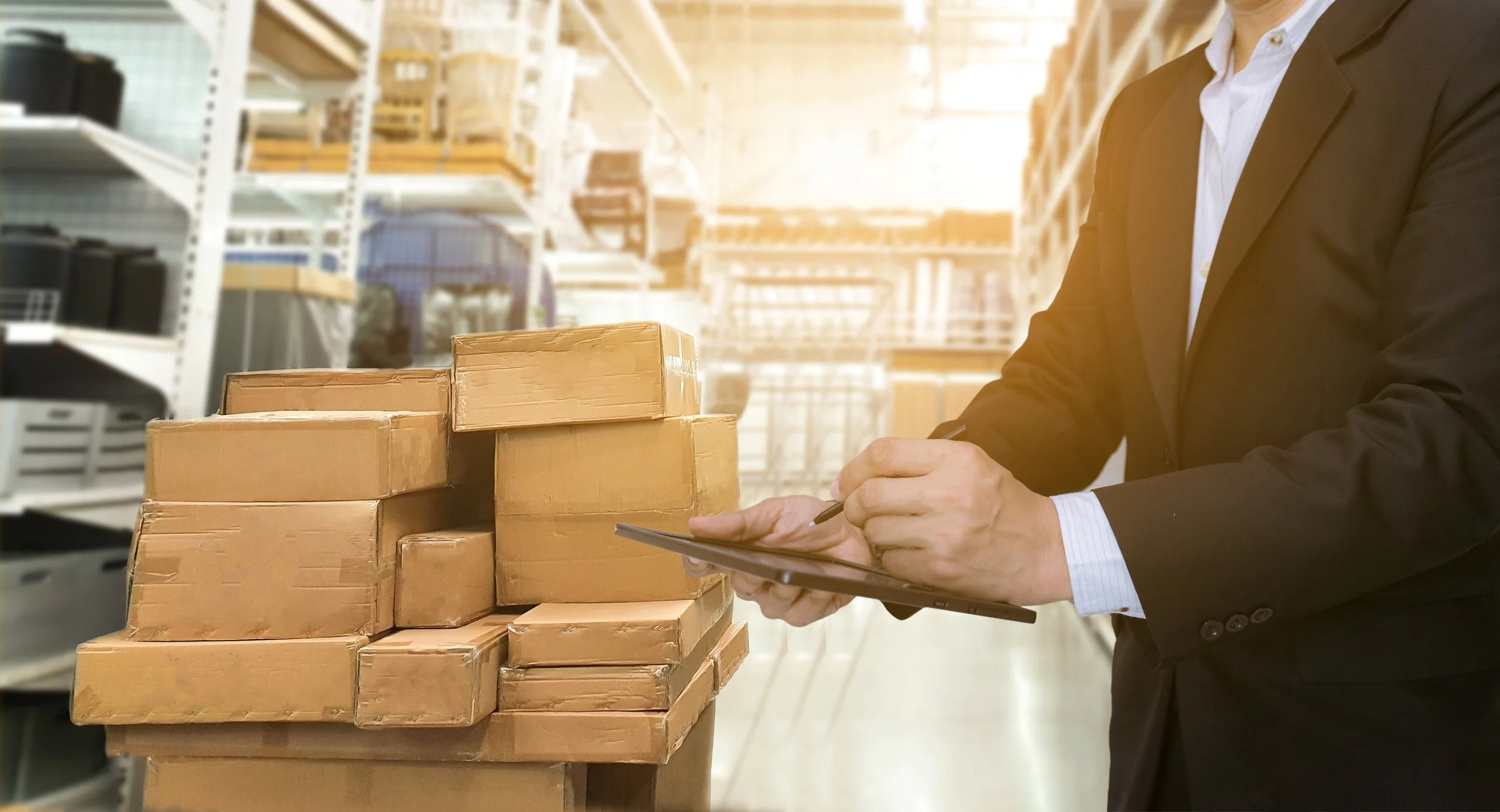 Man with tablet with boxes in a warehouse.
