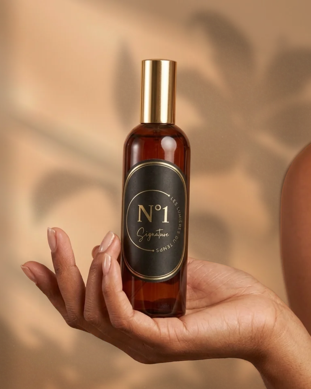 Une main tenant un flacon brun avec un bouchon doré et une étiquette noire avec des écritures dorées, portant la mention 'N°1 Signature'. par un fleuriste à Florange