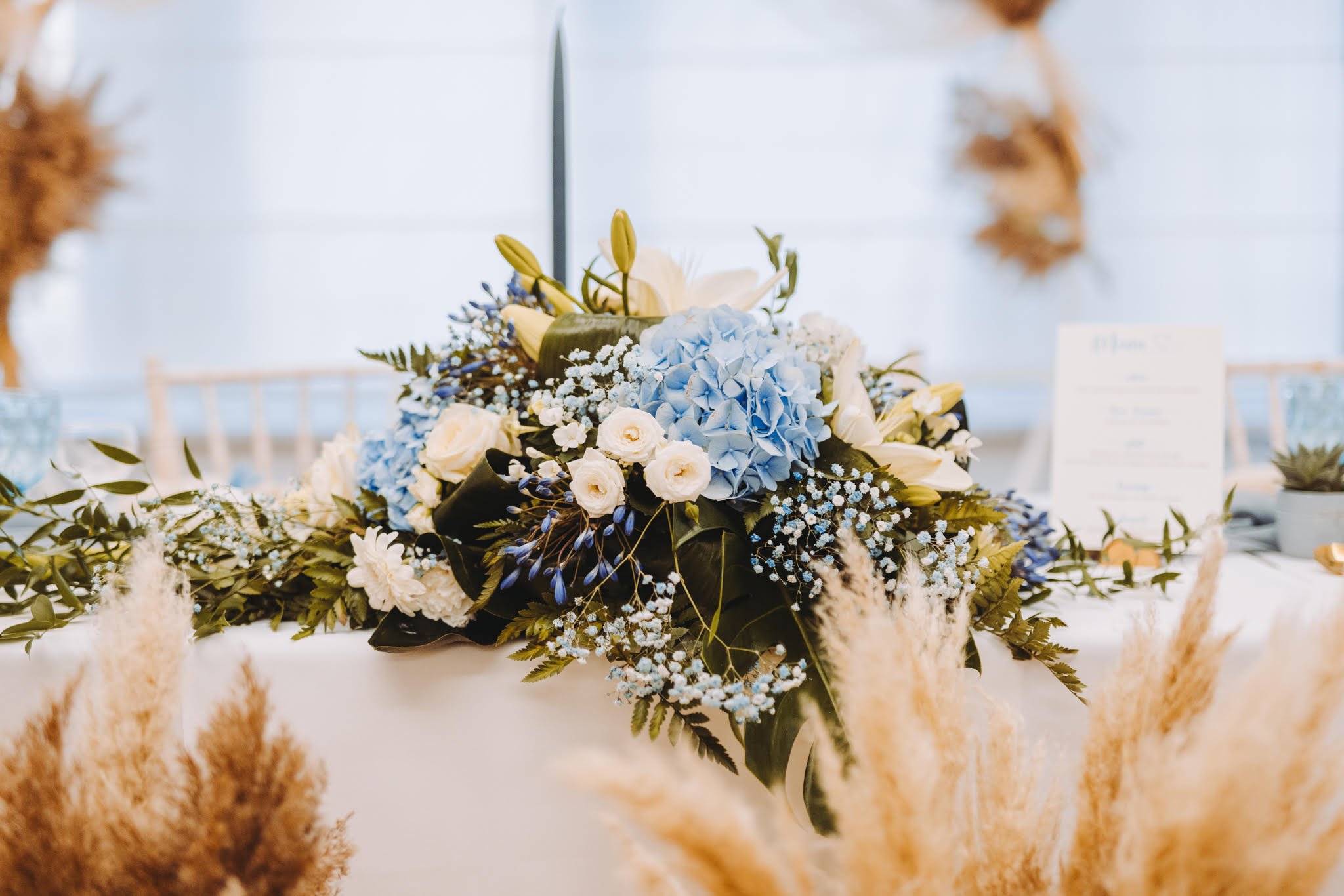 Centre de table composé de fleurs bleues, blanches et vertes sur une table lors d'un événement.