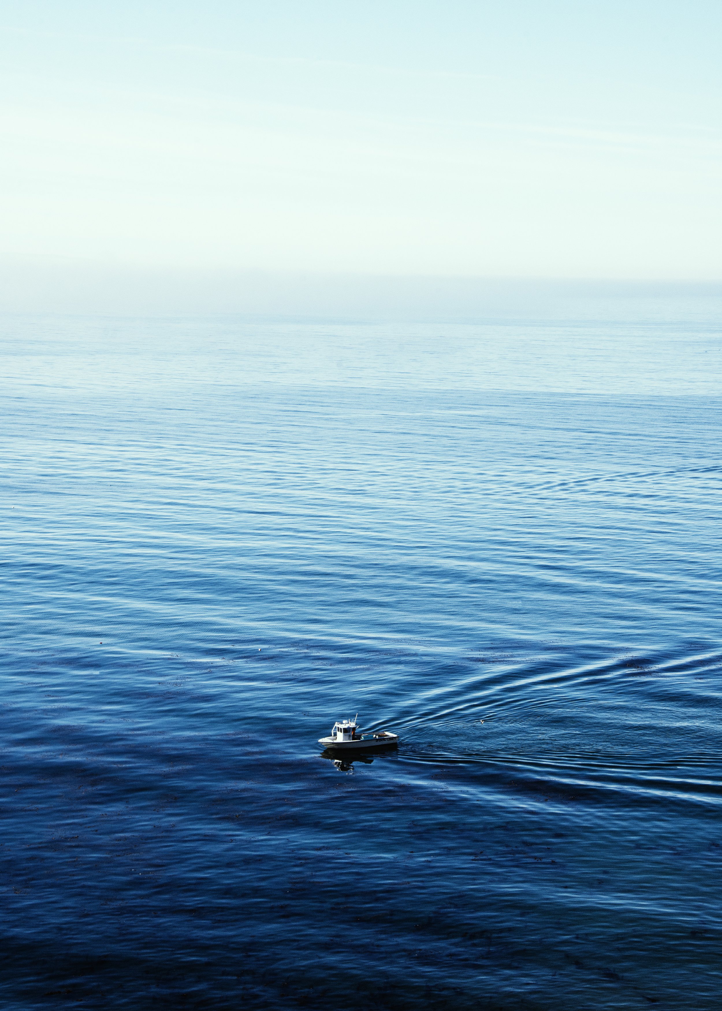 A boat floating on calm blue ocean water.