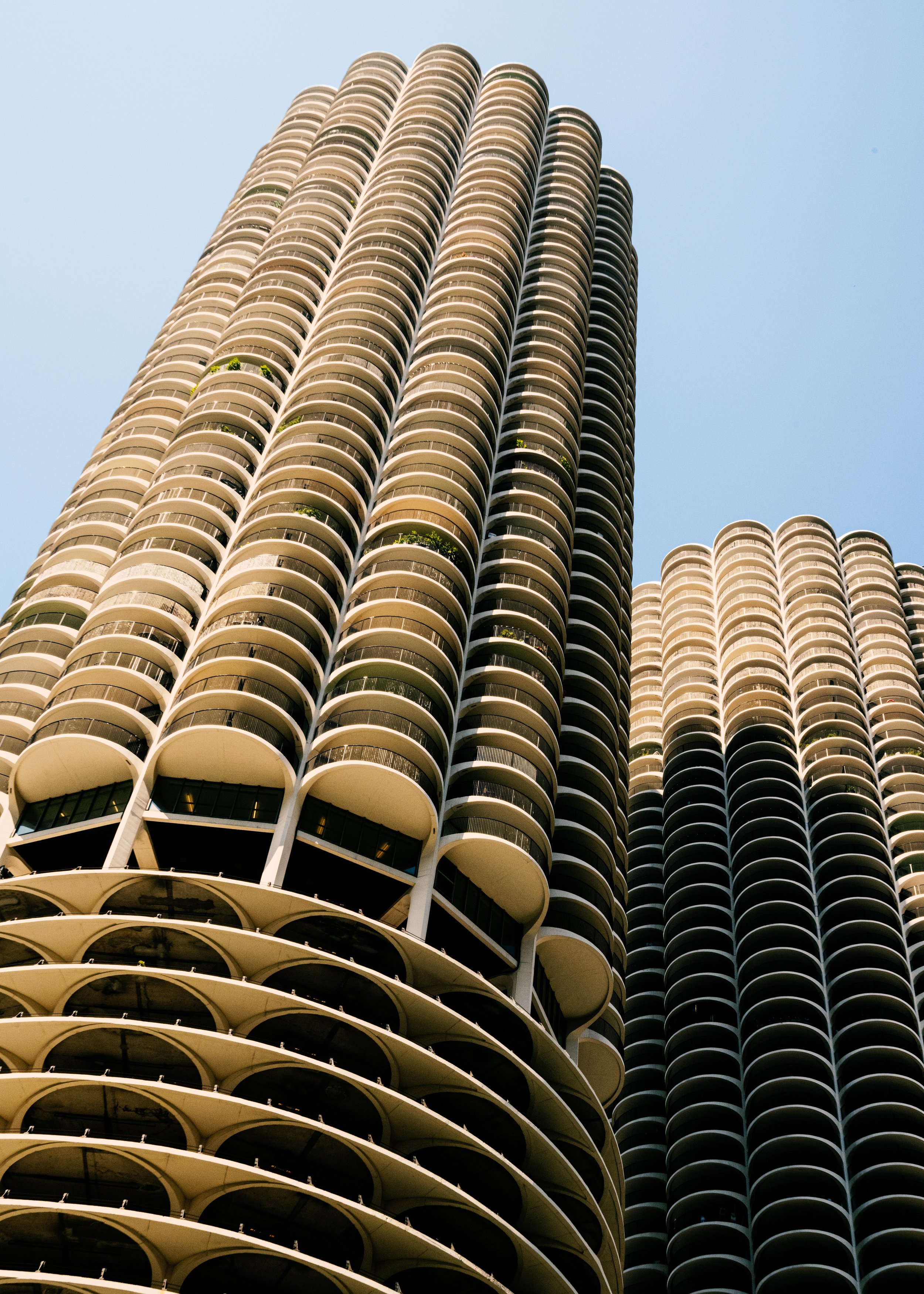Low angle view of modern high-rise residential or office building with rounded balconies on a sunny day against a clear blue sky.