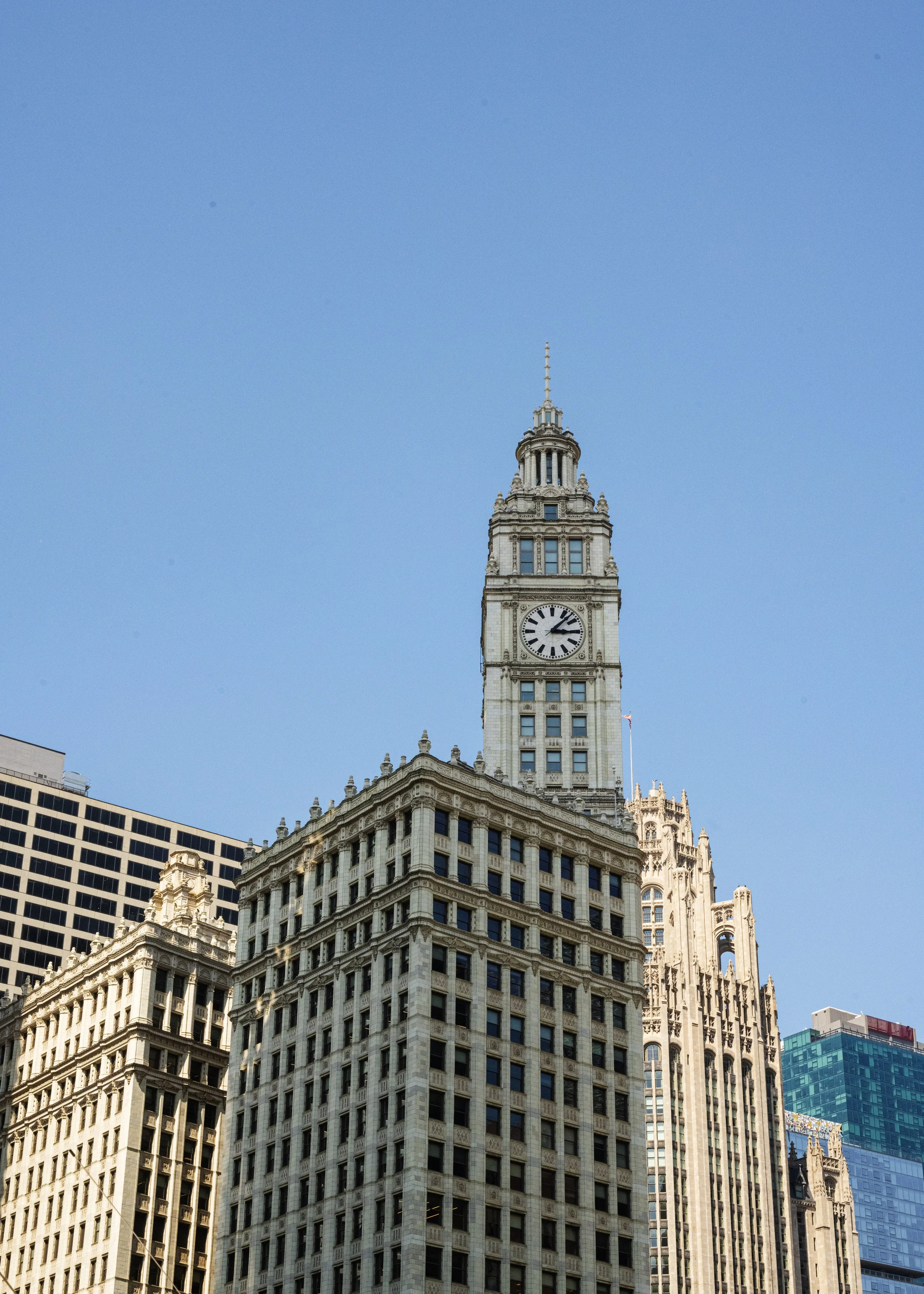 Tall historic clock tower building in downtown with blue sky background.