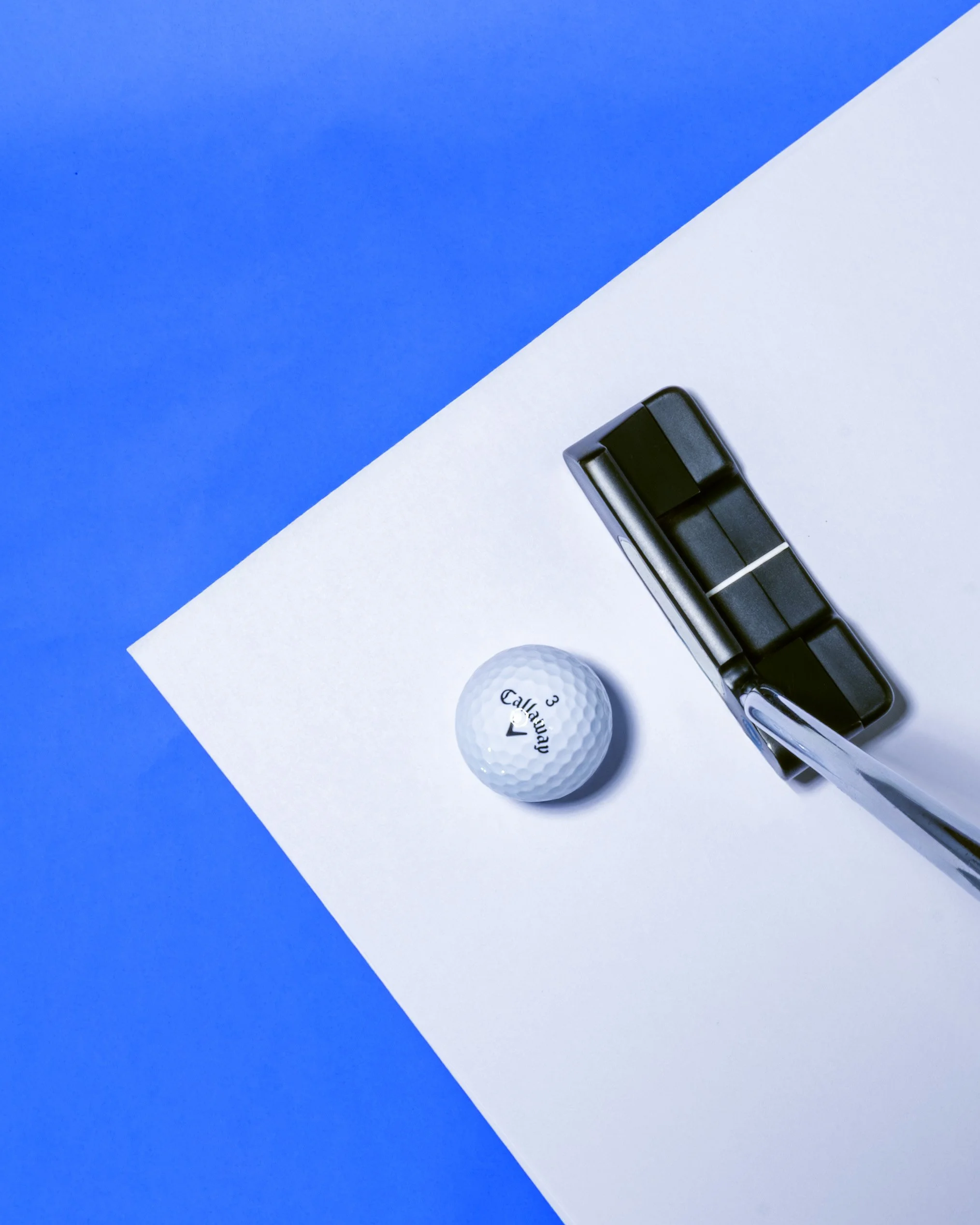 A golf ball, a marker, and a golf club on a white and blue background.